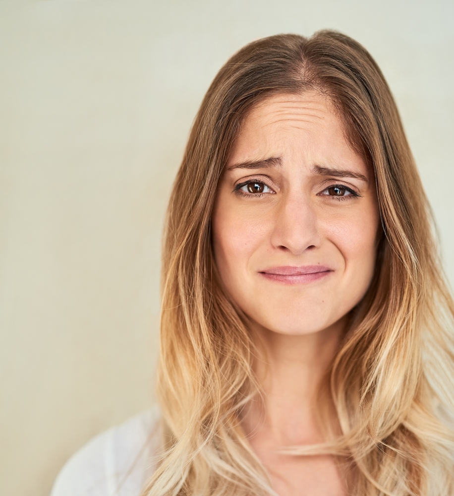 Face, woman and unhappy on portrait in studio background with unsure, uncertain and sad. Female person, isolated and facial expression or feeling for confused, disappointed and regret or emotional