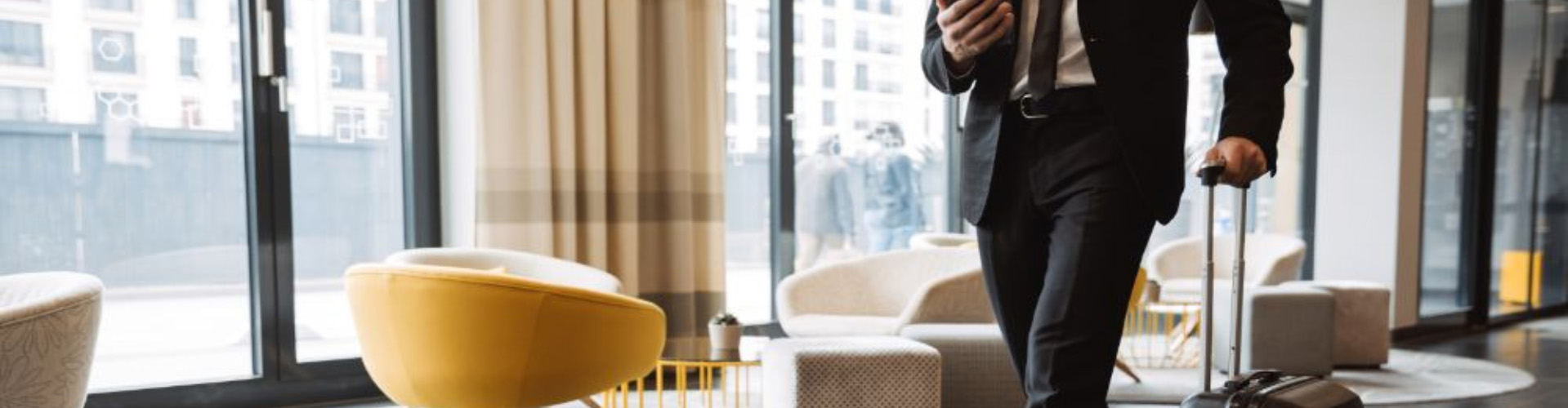 Man in a suit pushing suitcase through hotel reception area