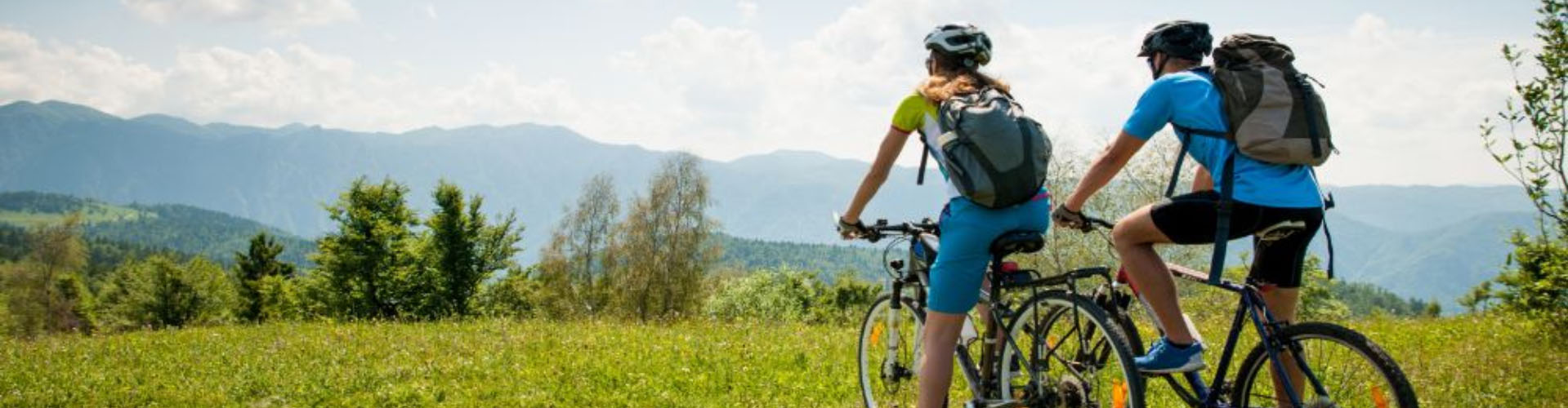 Two people on bikes at the top of a grassy mountain
