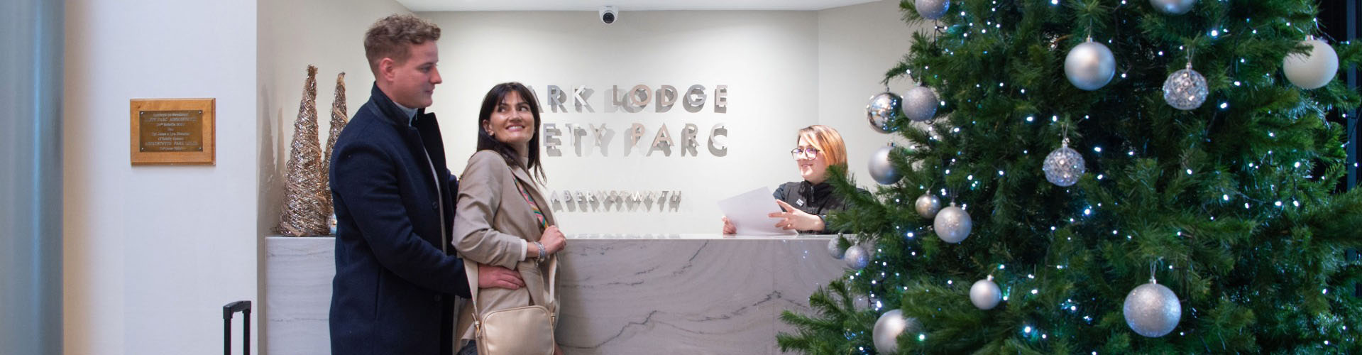 Guests arriving at Park Lodge Hotel Aberystwyth reception with Christmas tree decorations.