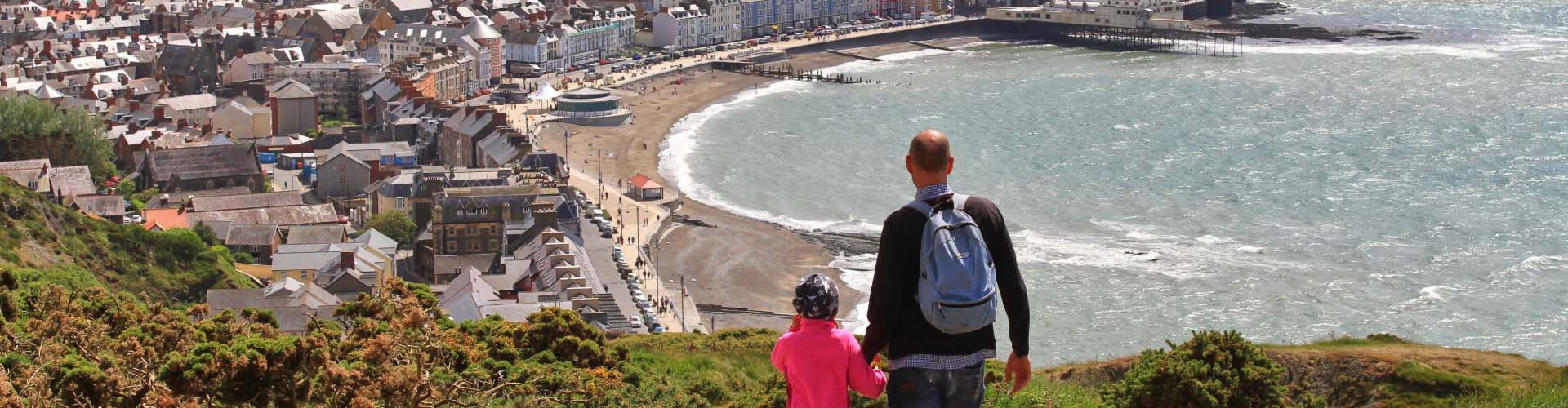 Father and child walking down Constitution Hill overlooking Aberystwyth promenade.