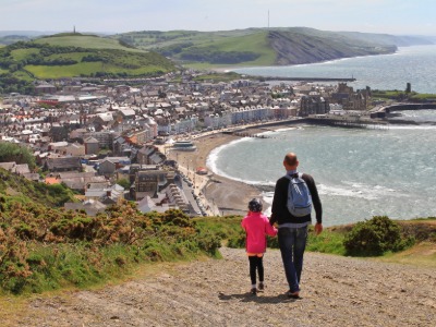 Father and child walking down Constitution Hill overlooking Aberystwyth promenade.