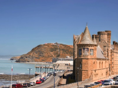 Aberystwyth Old College castle building with Constitution Hill and Cardigan Bay coastline on a sunny