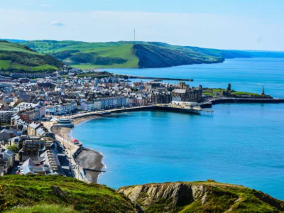 Aerial shot of the Aberystwyth coastline with the sandy beach and blue sea on a sunny day