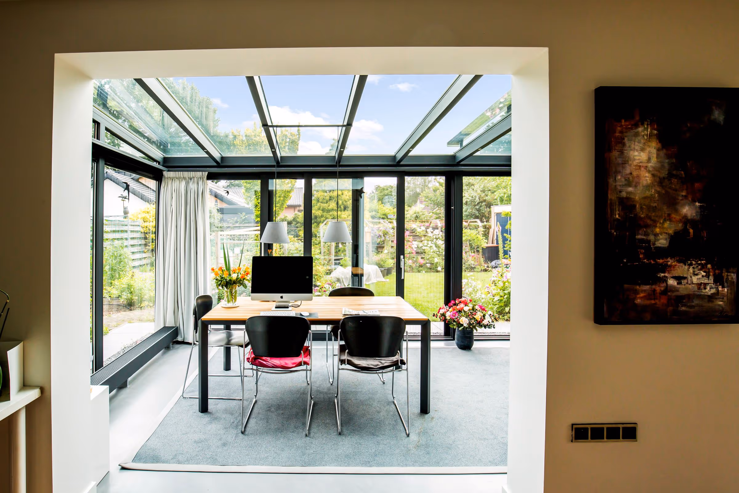 Moderne serre werkruimte met glazen dak en bureau, met uitzicht op de tuin
