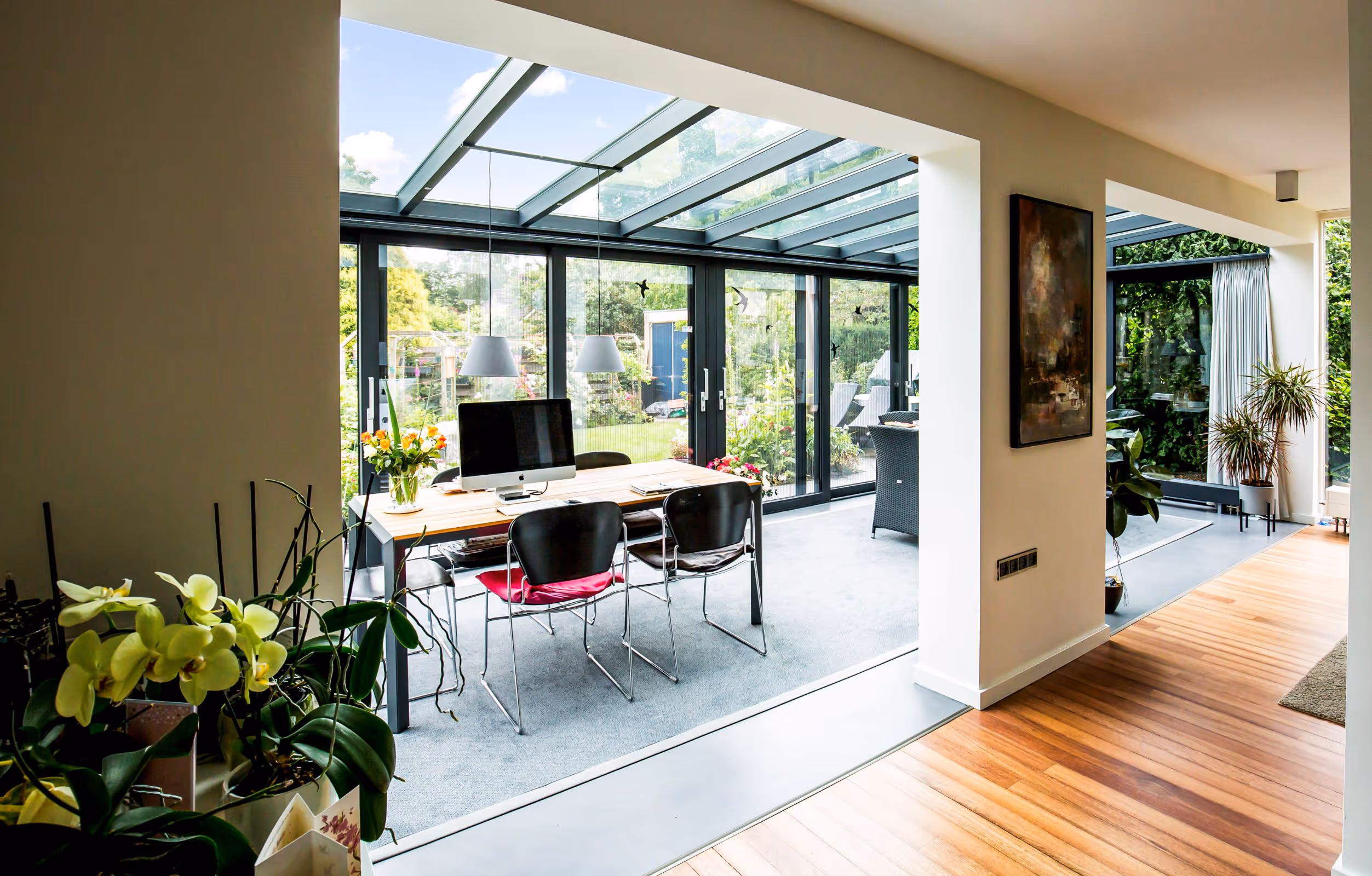 Open tuinkamer met glazen wanden en werkplek, verbonden met de woonkamer