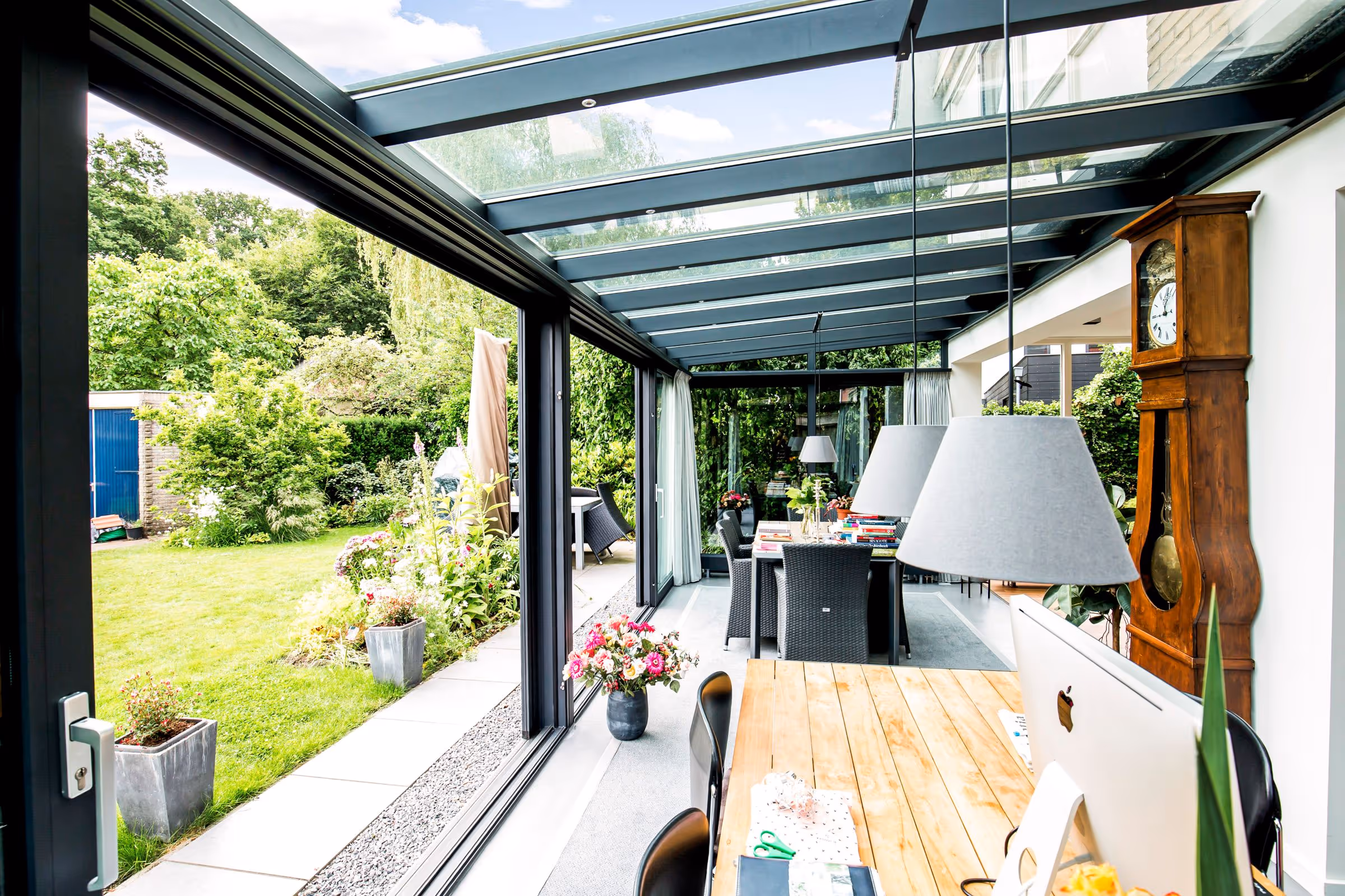Serre met glazen dak en werkplek, met veel natuurlijk licht en uitzicht op de tuin