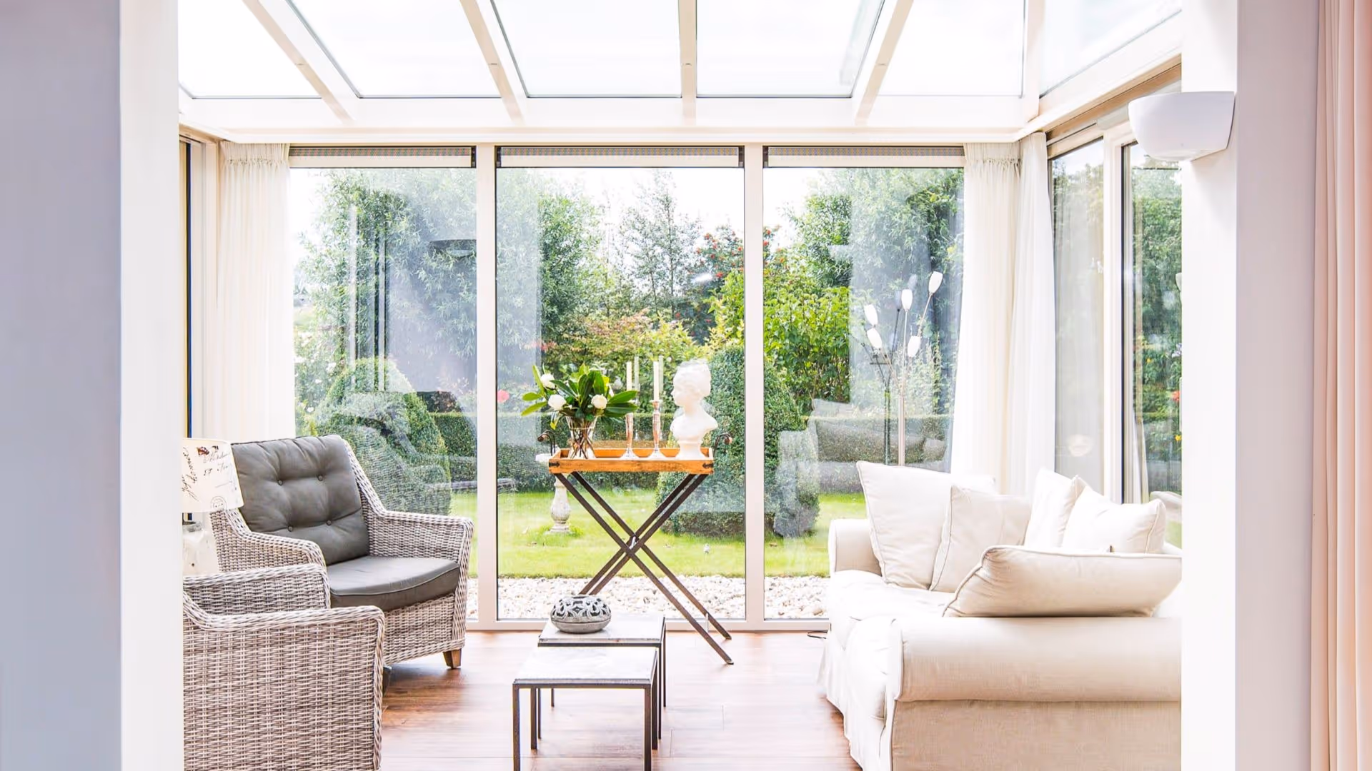 Lichte serre interieur met grote glazen schuifpuien en uitzicht op een groene tuin