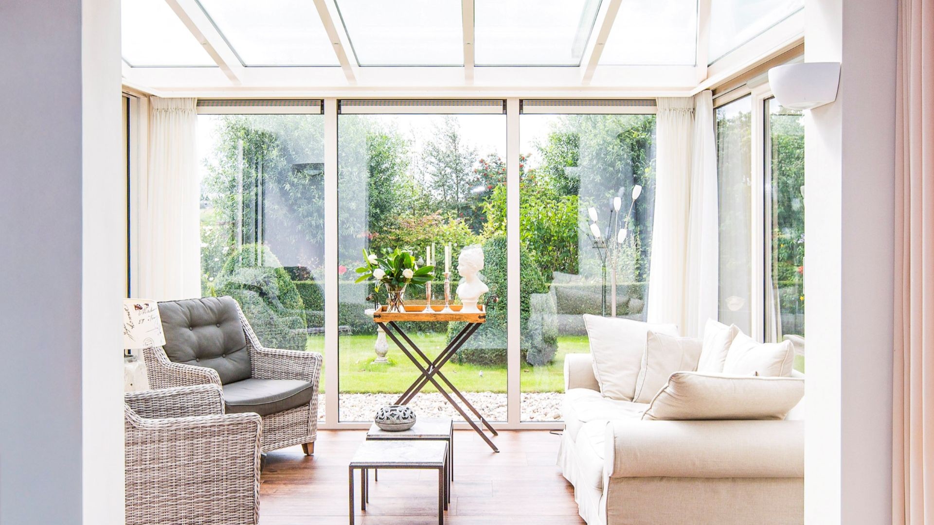 Lichte serre interieur met grote glazen schuifpuien en uitzicht op een groene tuin
