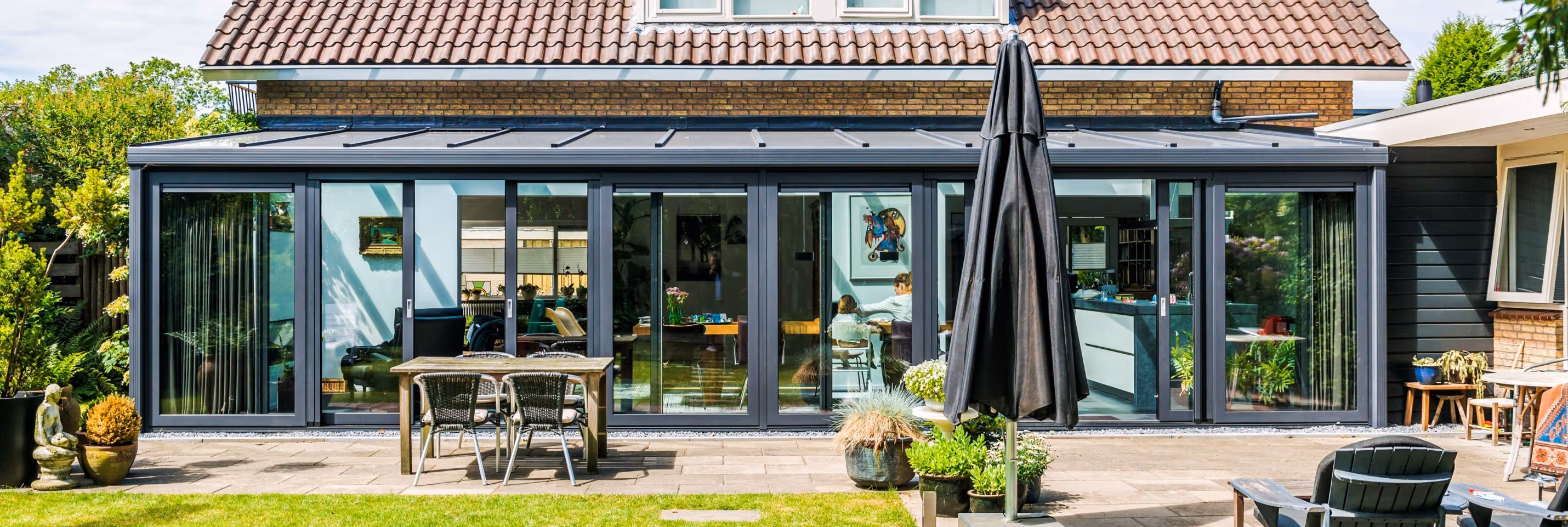 Achterzijde woning met brede serre en volledig glazen schuifpuien