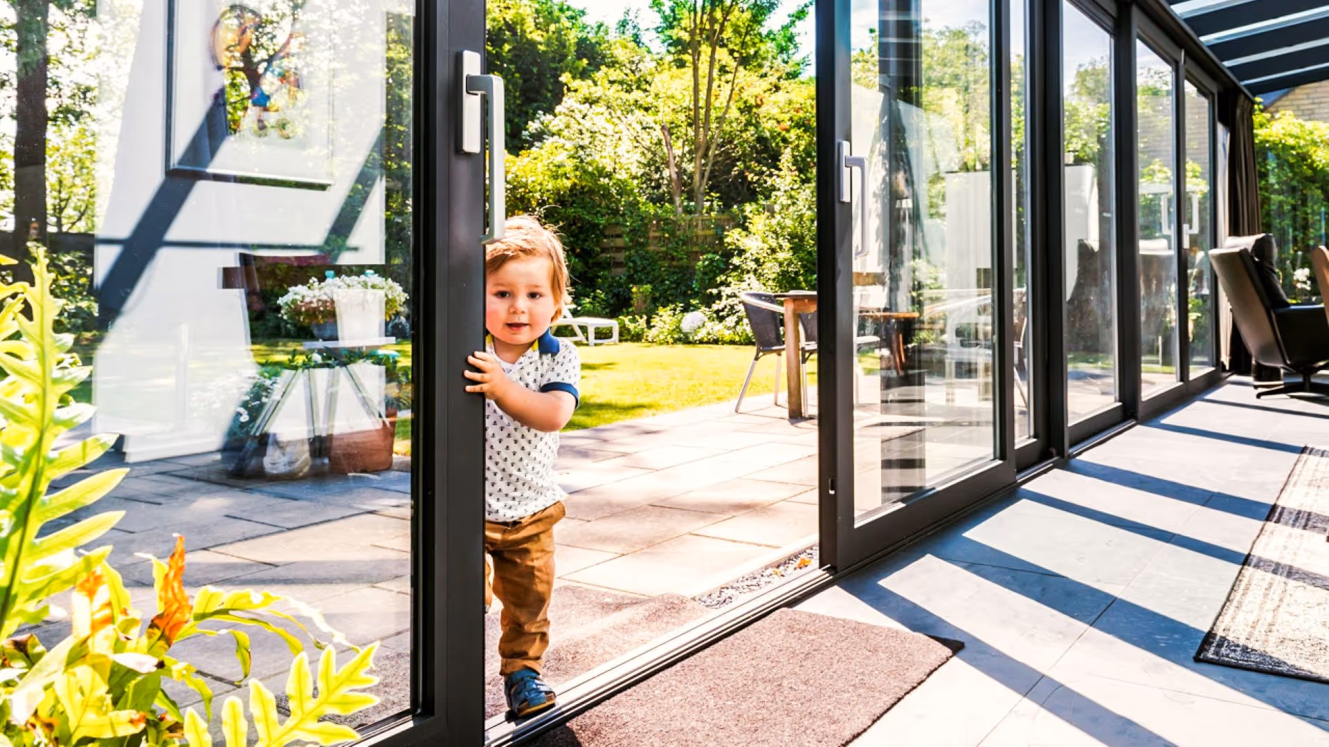 Moderne serre met glazen schuifpui die direct toegang geeft tot de tuin