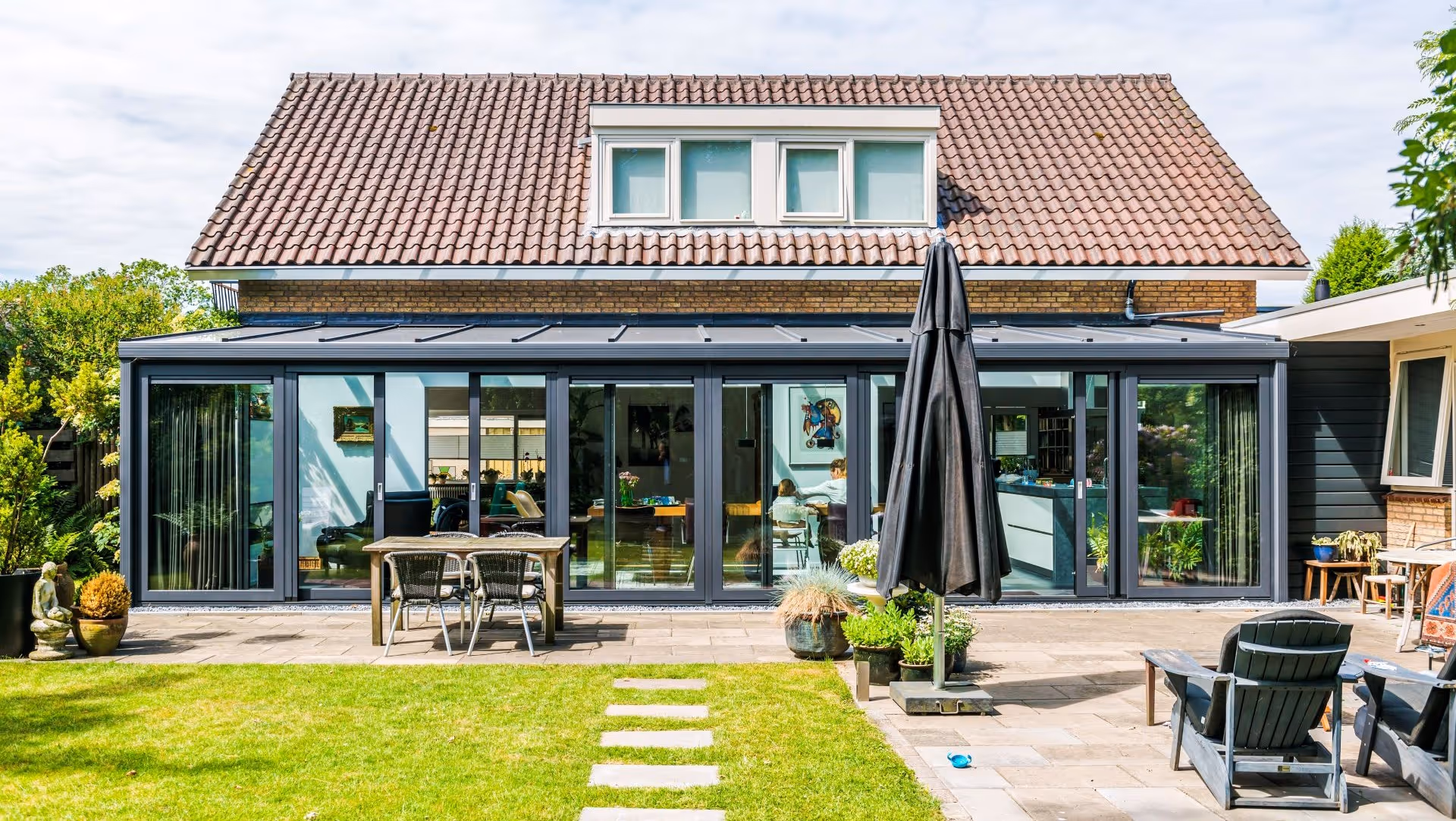 Moderne serre over volledige breedte van de woning met glazen wanden