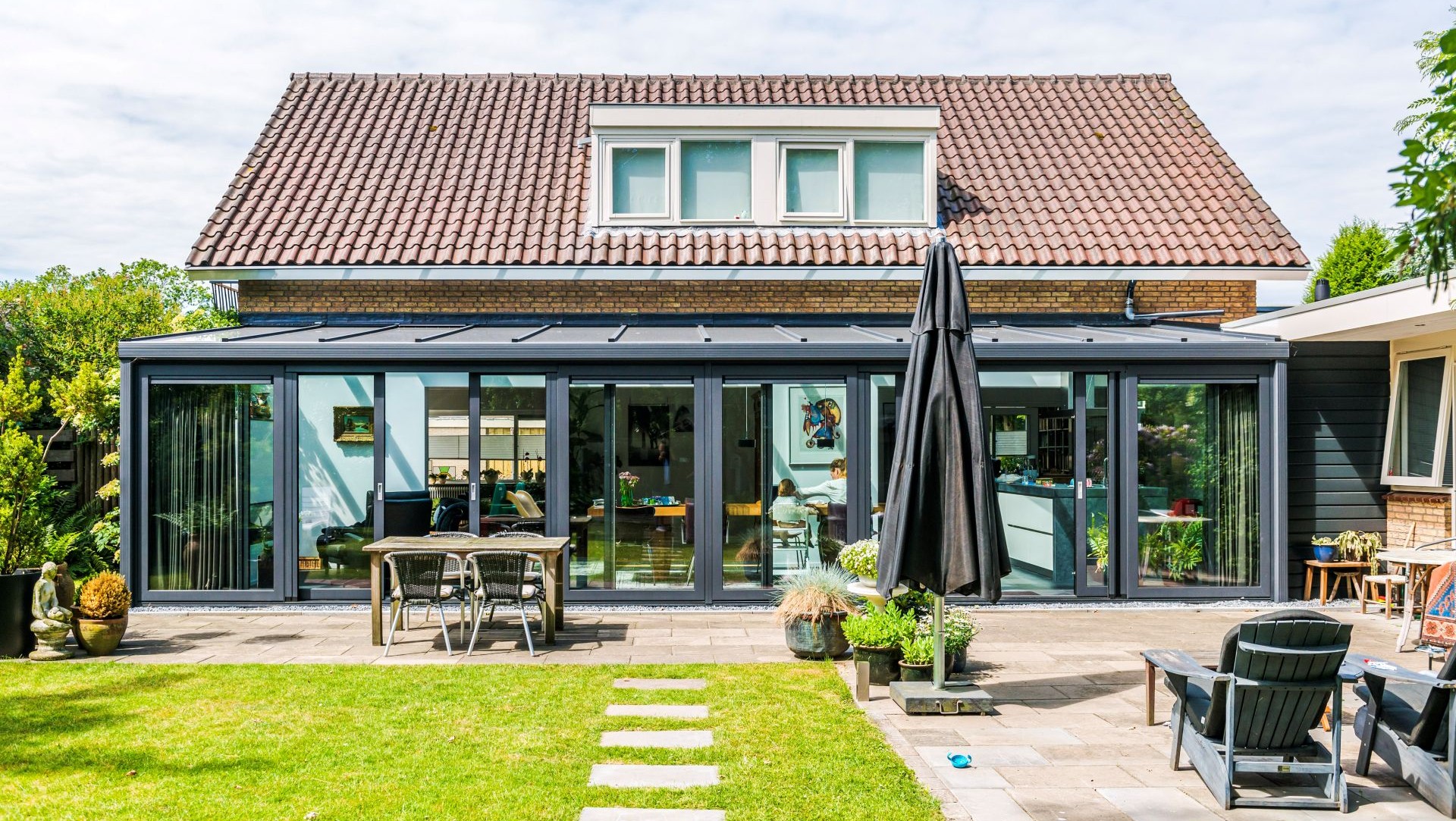 Moderne serre over volledige breedte van de woning met glazen wanden
