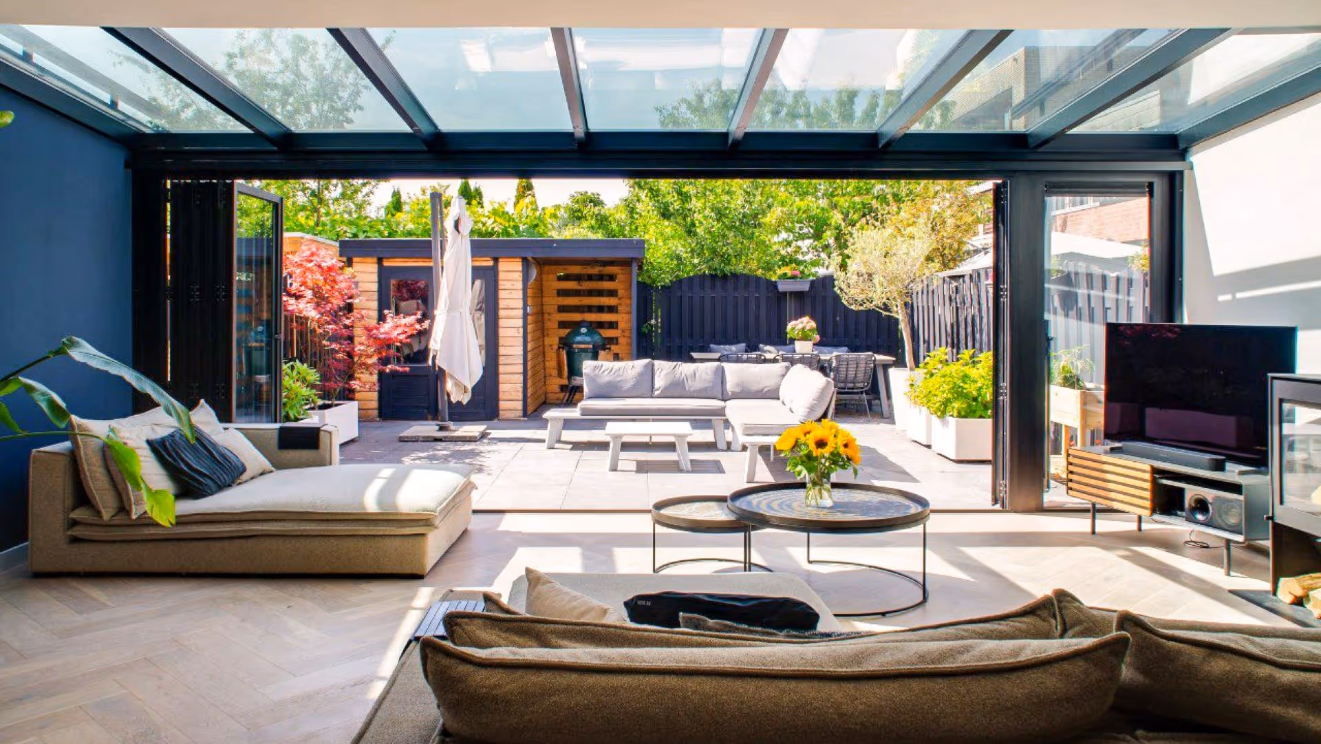 Luxe serre aanbouw met volledig open te schuiven glazen pui en naadloze overgang naar terras