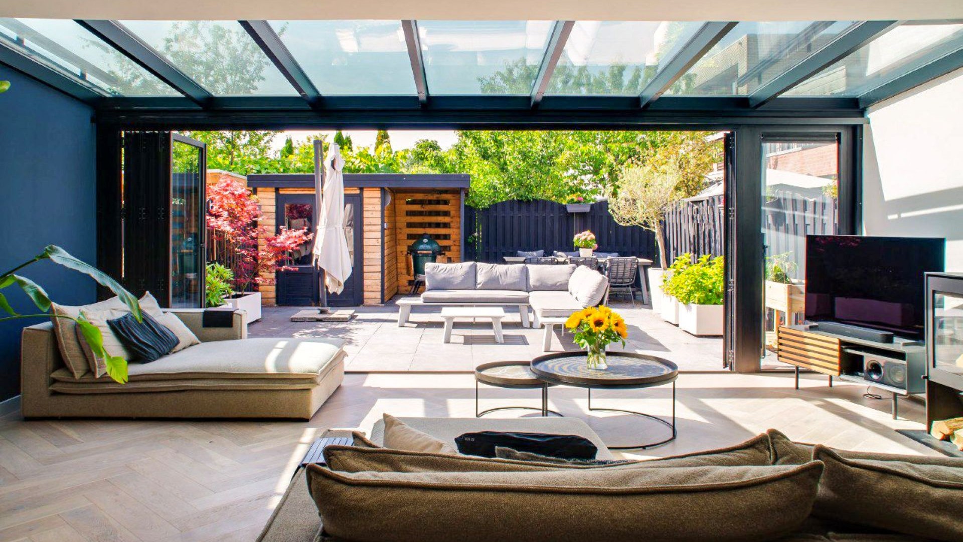 Luxe serre aanbouw met volledig open te schuiven glazen pui en naadloze overgang naar terras