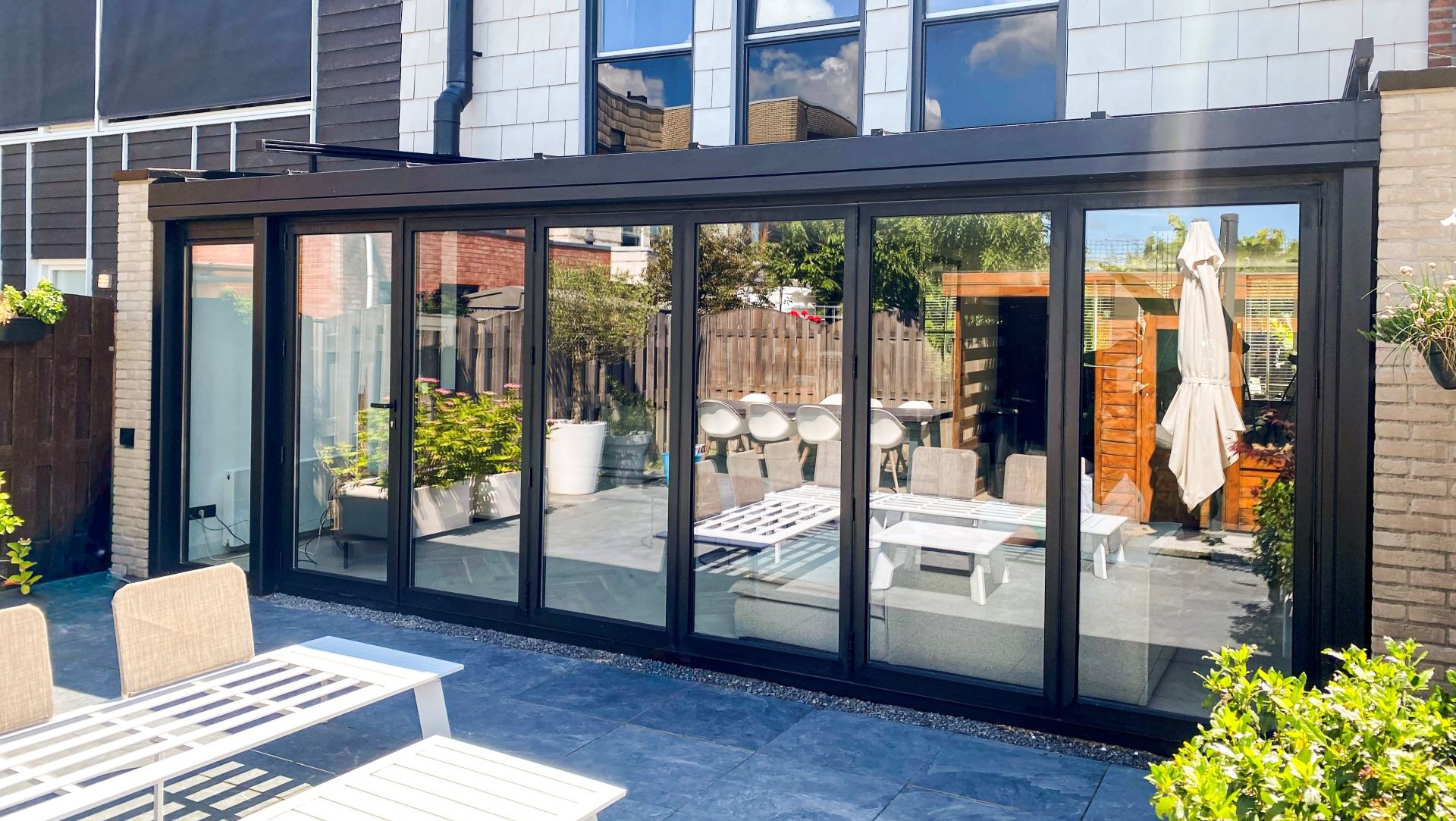 Brede serre met glazen schuifwand over de volledige gevel en uitzicht op de tuin