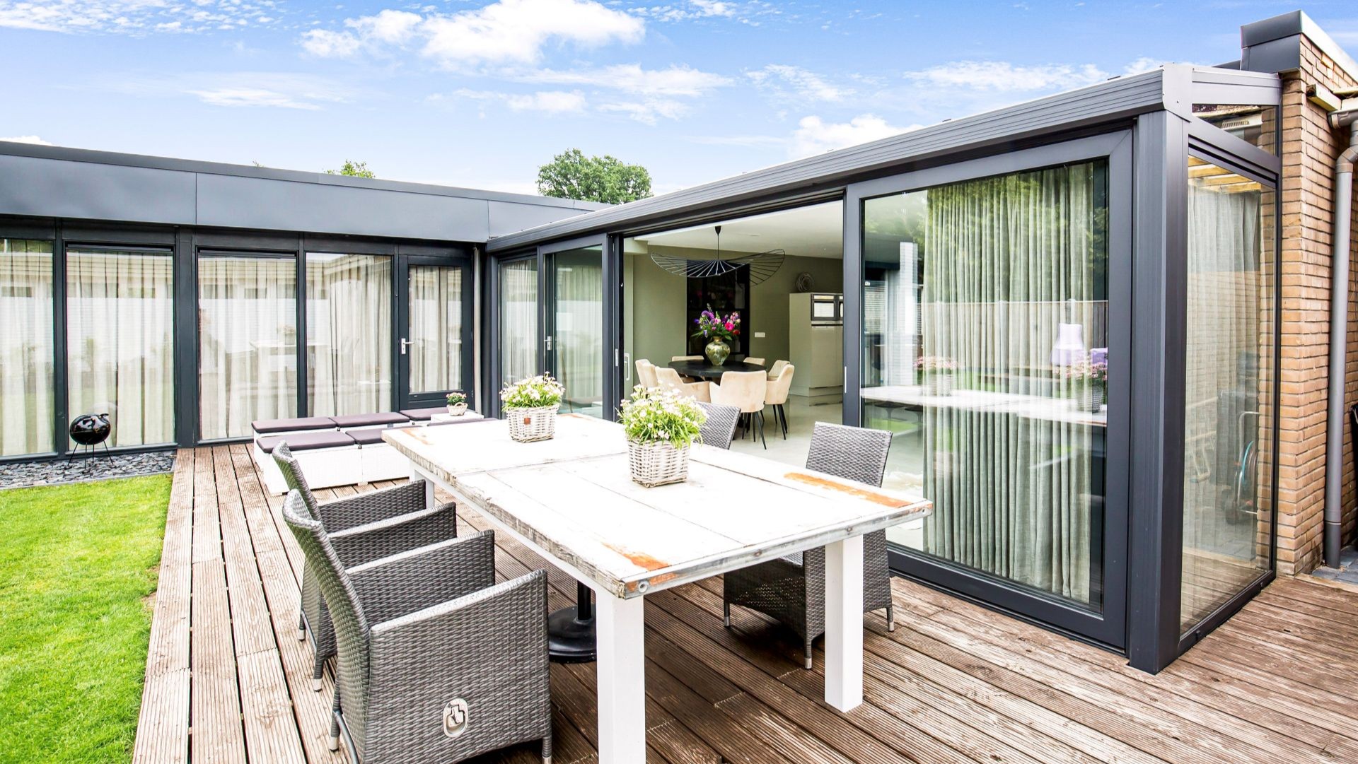 Terras met uitzicht op serre met glazen schuifdeuren