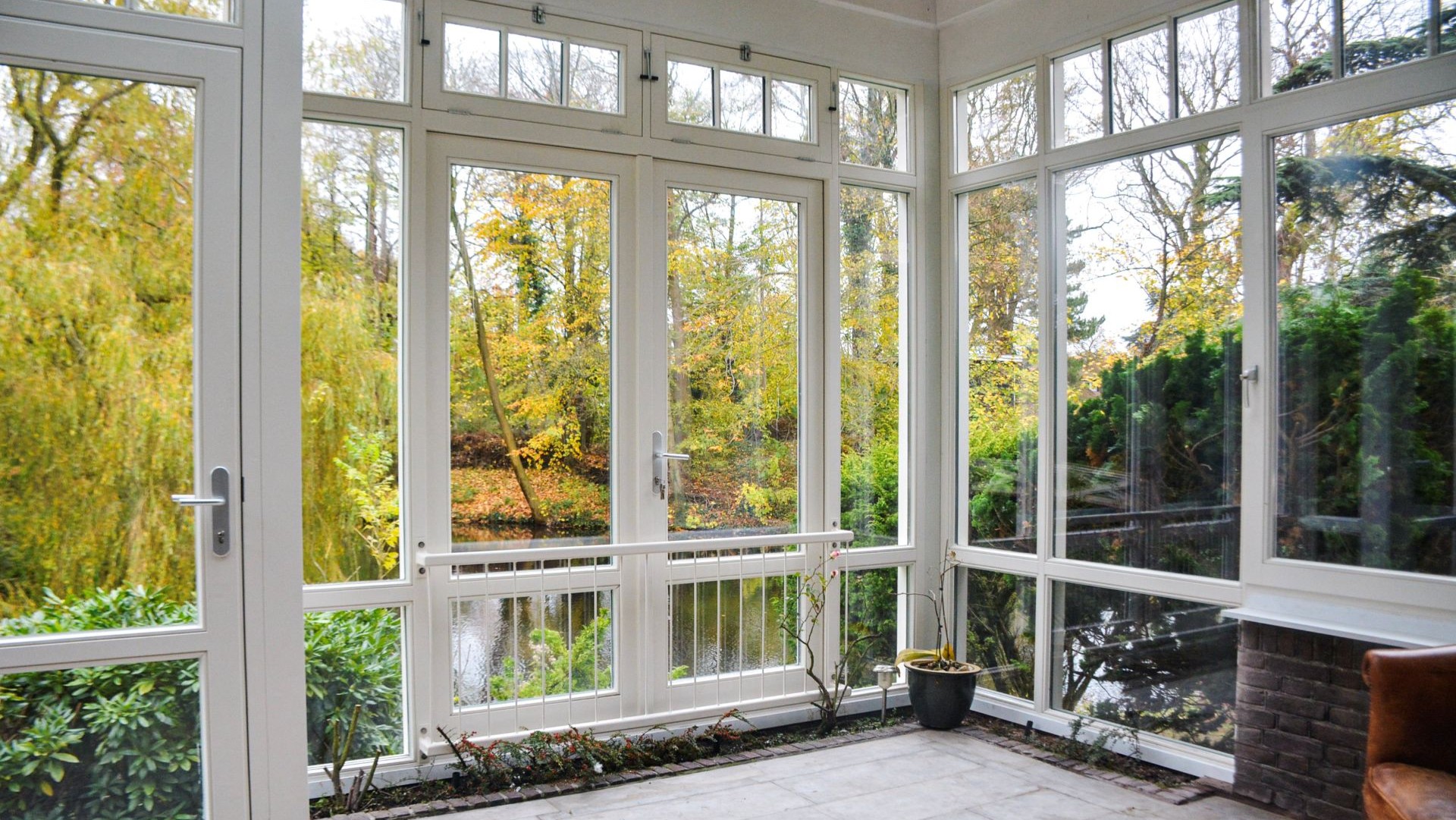 Lichte serre ruimte met grote ramen en uitzicht op tuin en water in natuurlijke omgeving