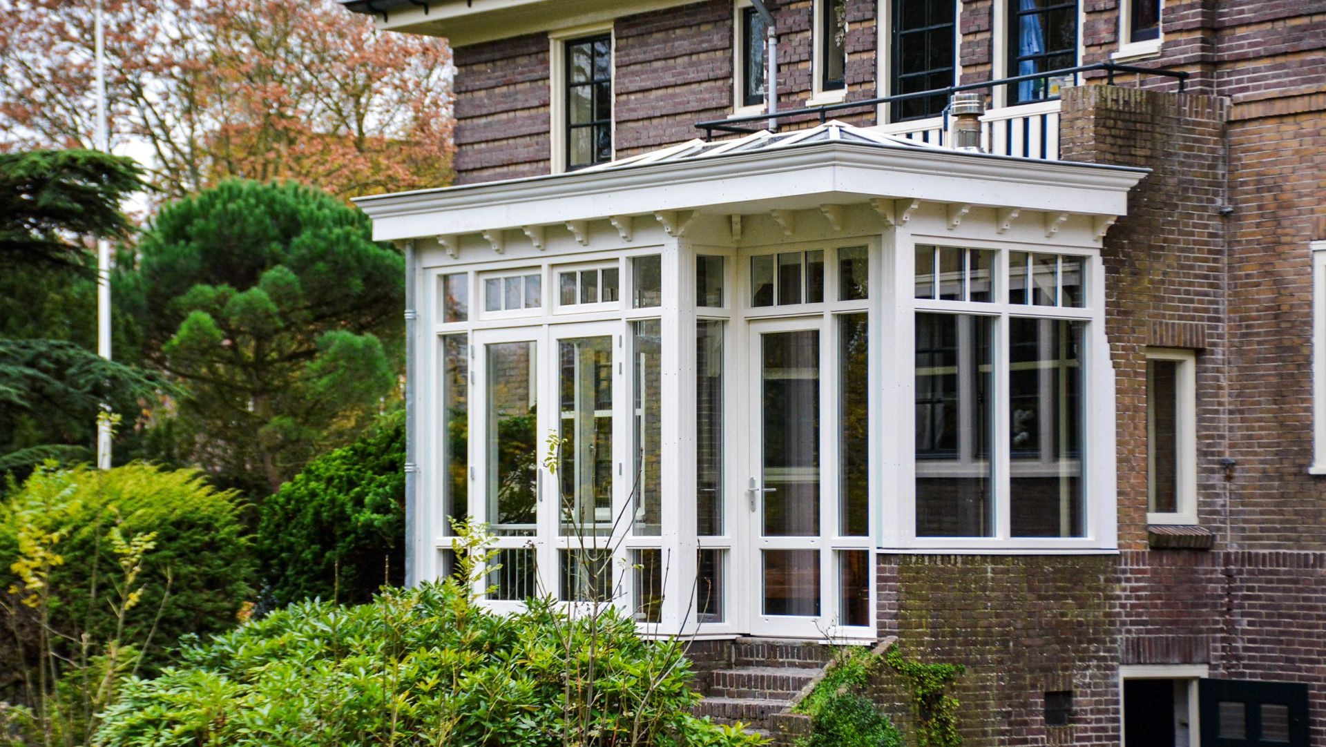 Stijlvolle serre aanbouw met houten kozijnen en grote ramen, omringd door groene tuin in Heemstede