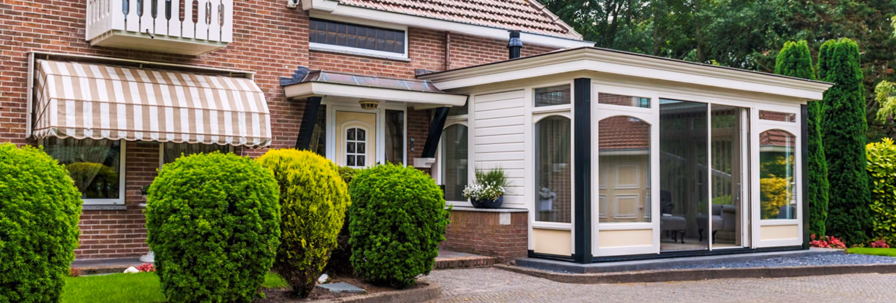 Serre aan woning met klassieke uitstraling, grote glaspartijen en verzorgde tuin