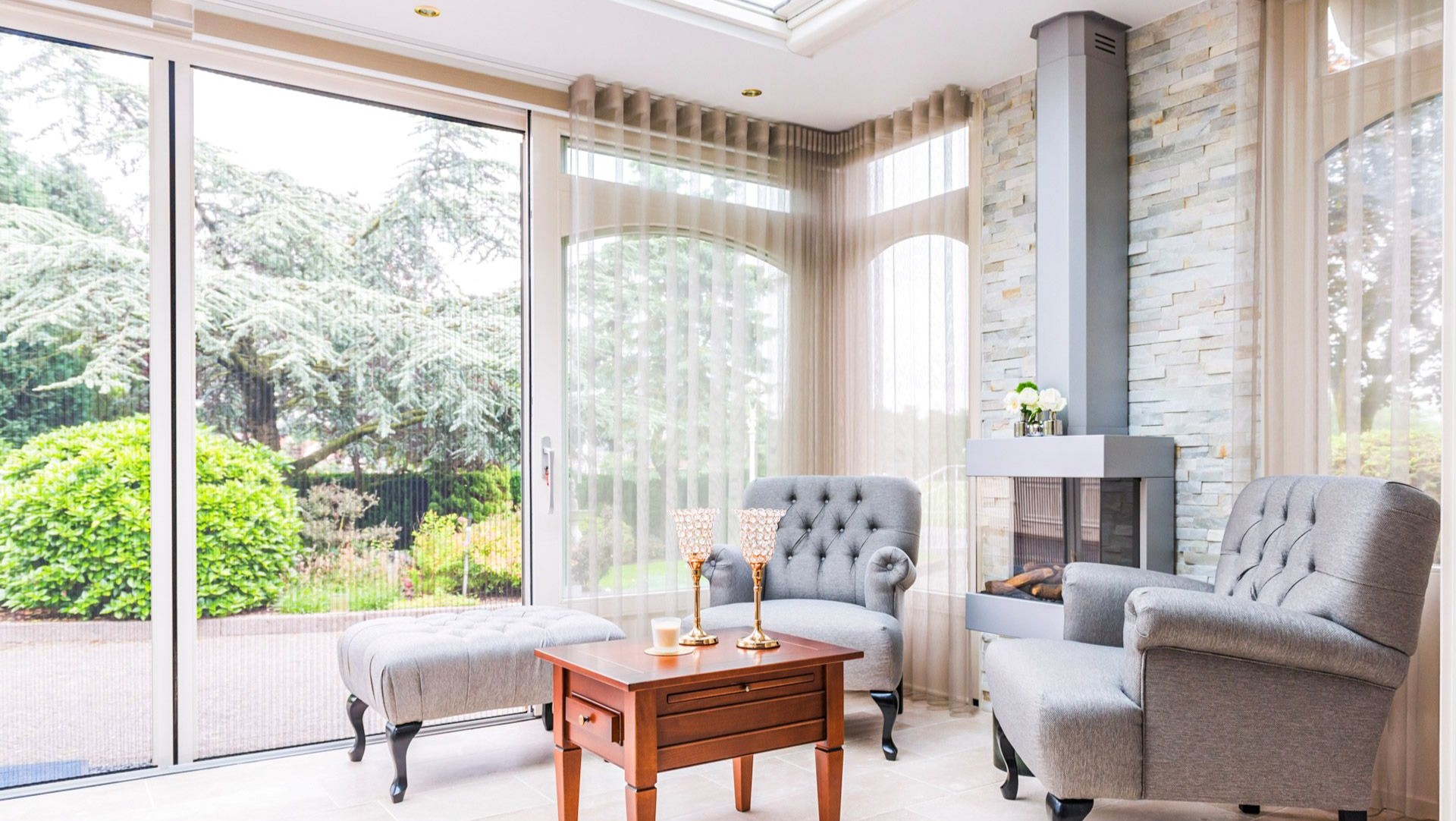 Klassieke serre met grote schuifpui, lichte inrichting en uitzicht op groene tuin