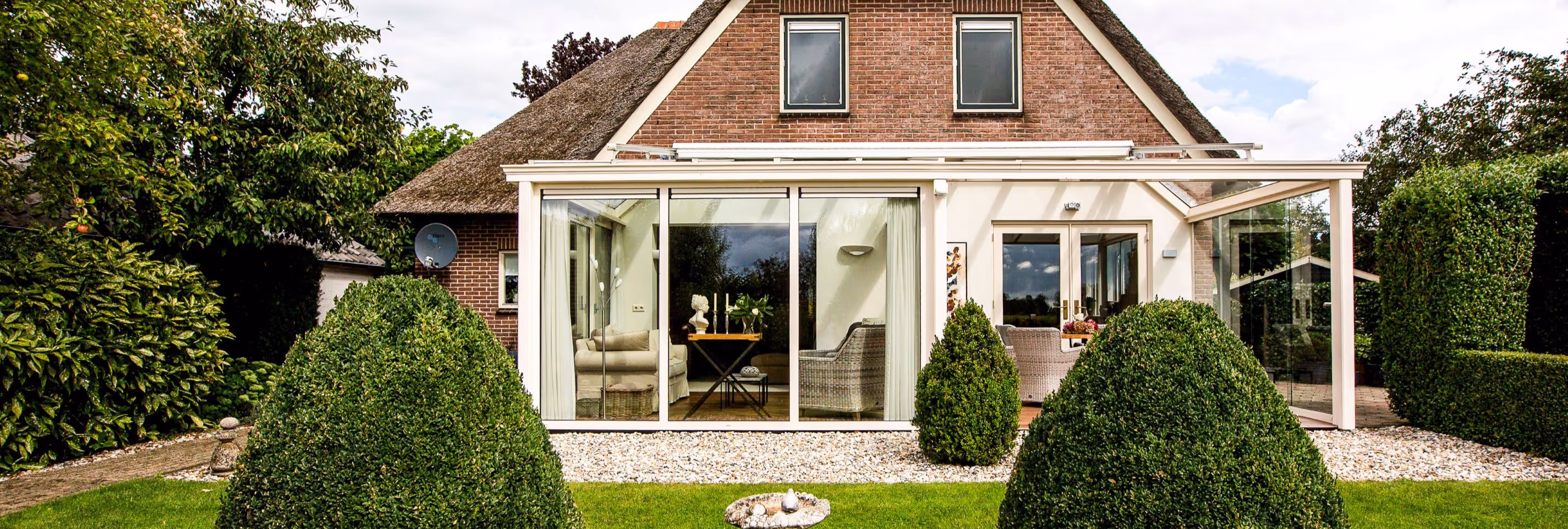 Moderne tuinkamer met glazen schuifwanden en overkapping, grenzend aan de tuin
