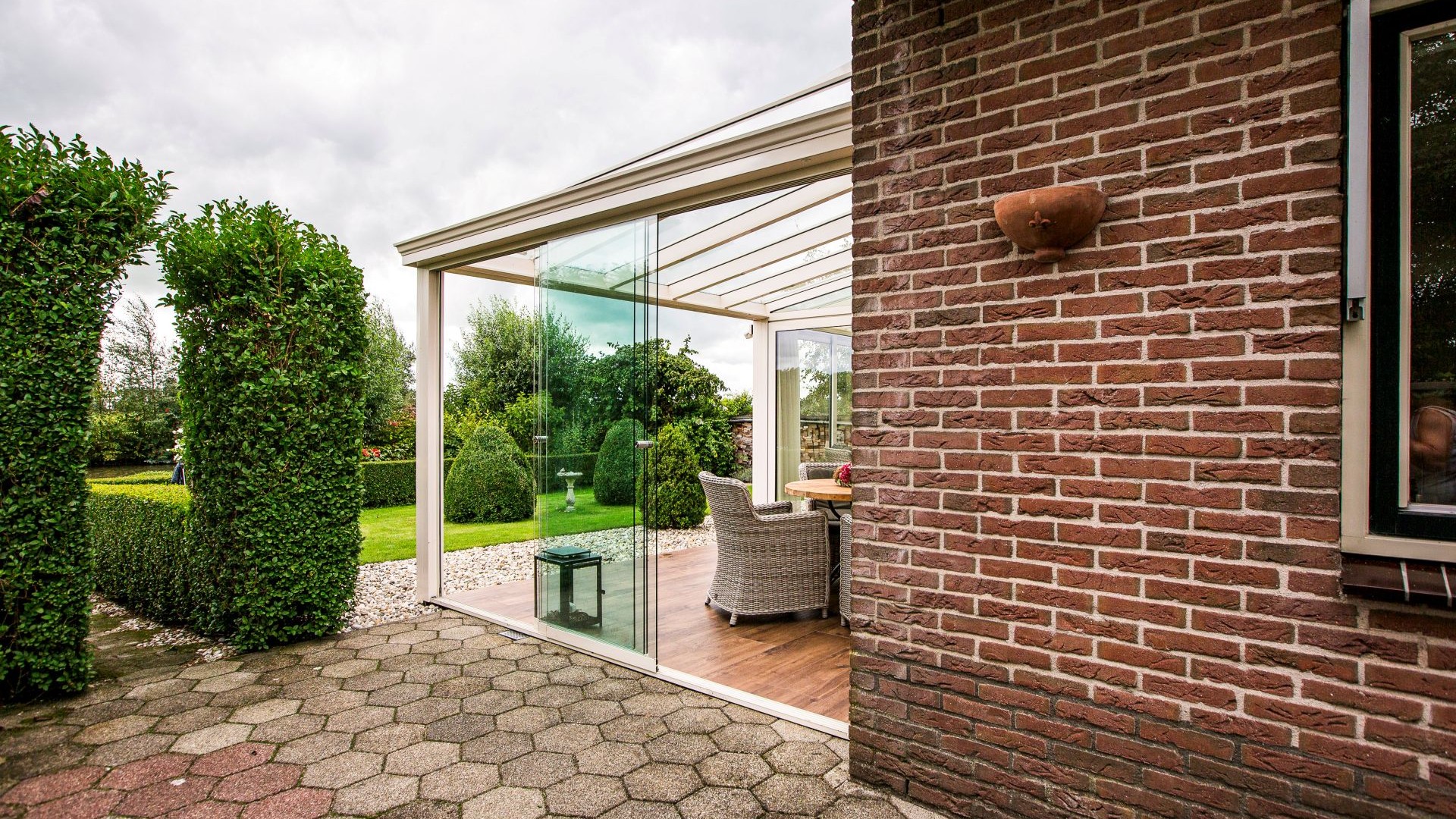 Tuinkamer met glazen schuifwanden en sfeervol ingericht terrasgedeelte