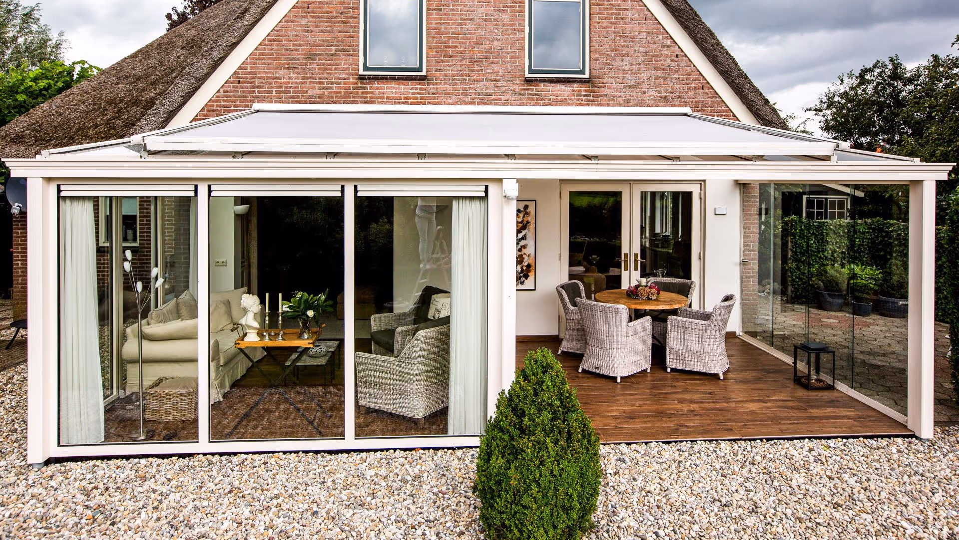 Tuinkamer met glazen schuifwanden en gedeeltelijk overdekt terras met zitgedeelte