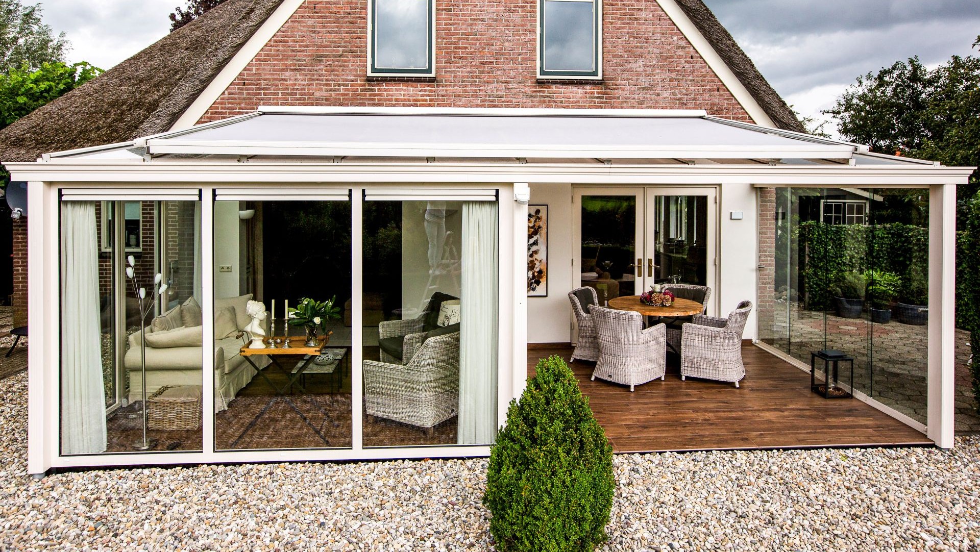Tuinkamer met glazen schuifwanden en gedeeltelijk overdekt terras met zitgedeelte
