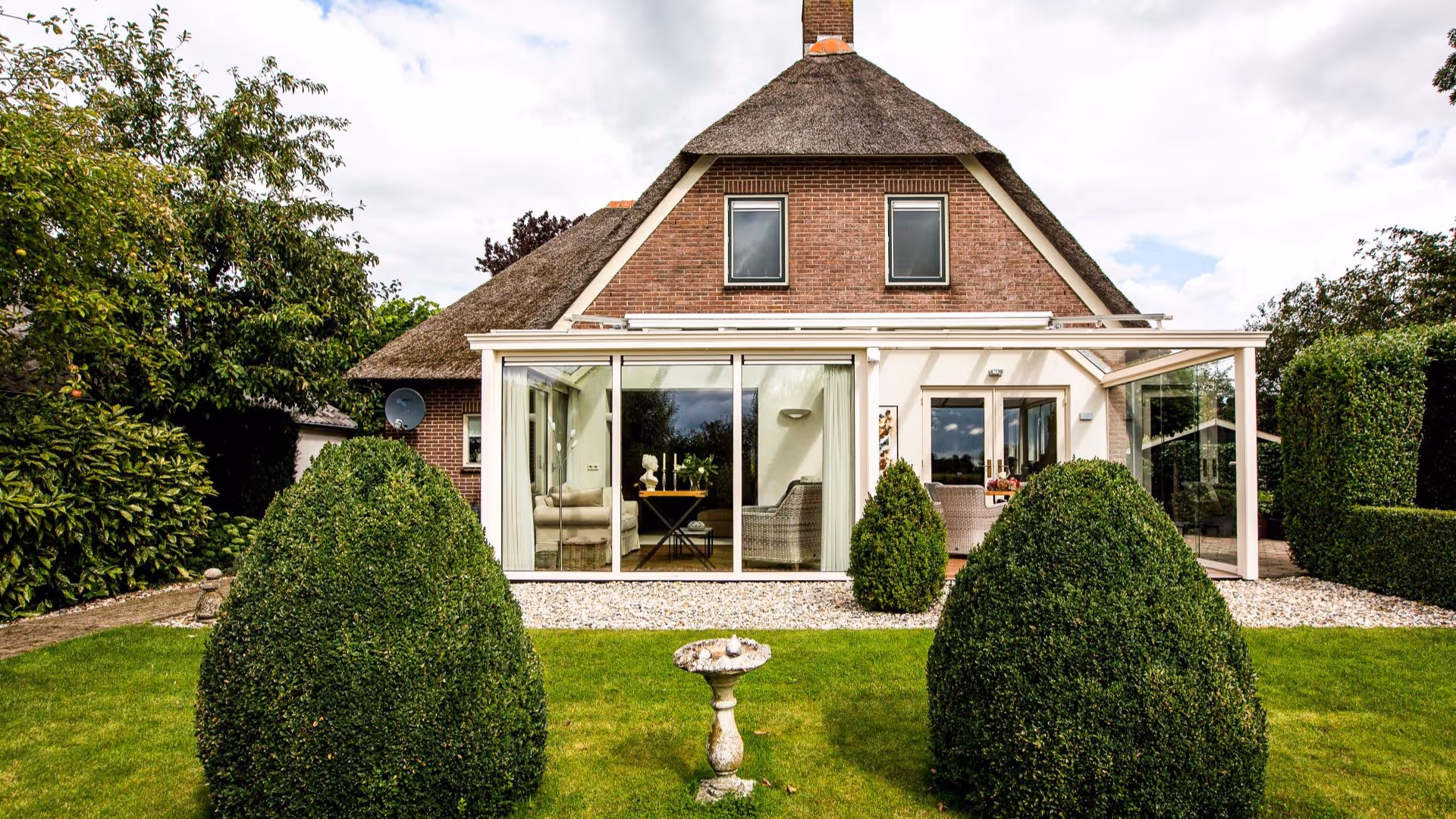 Aluminium tuinkamer met glazen schuifwanden en comfortabel ingerichte zithoek