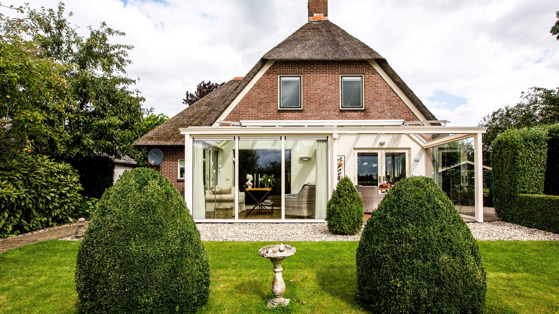 Aluminium tuinkamer met glazen schuifwanden en comfortabel ingerichte zithoek