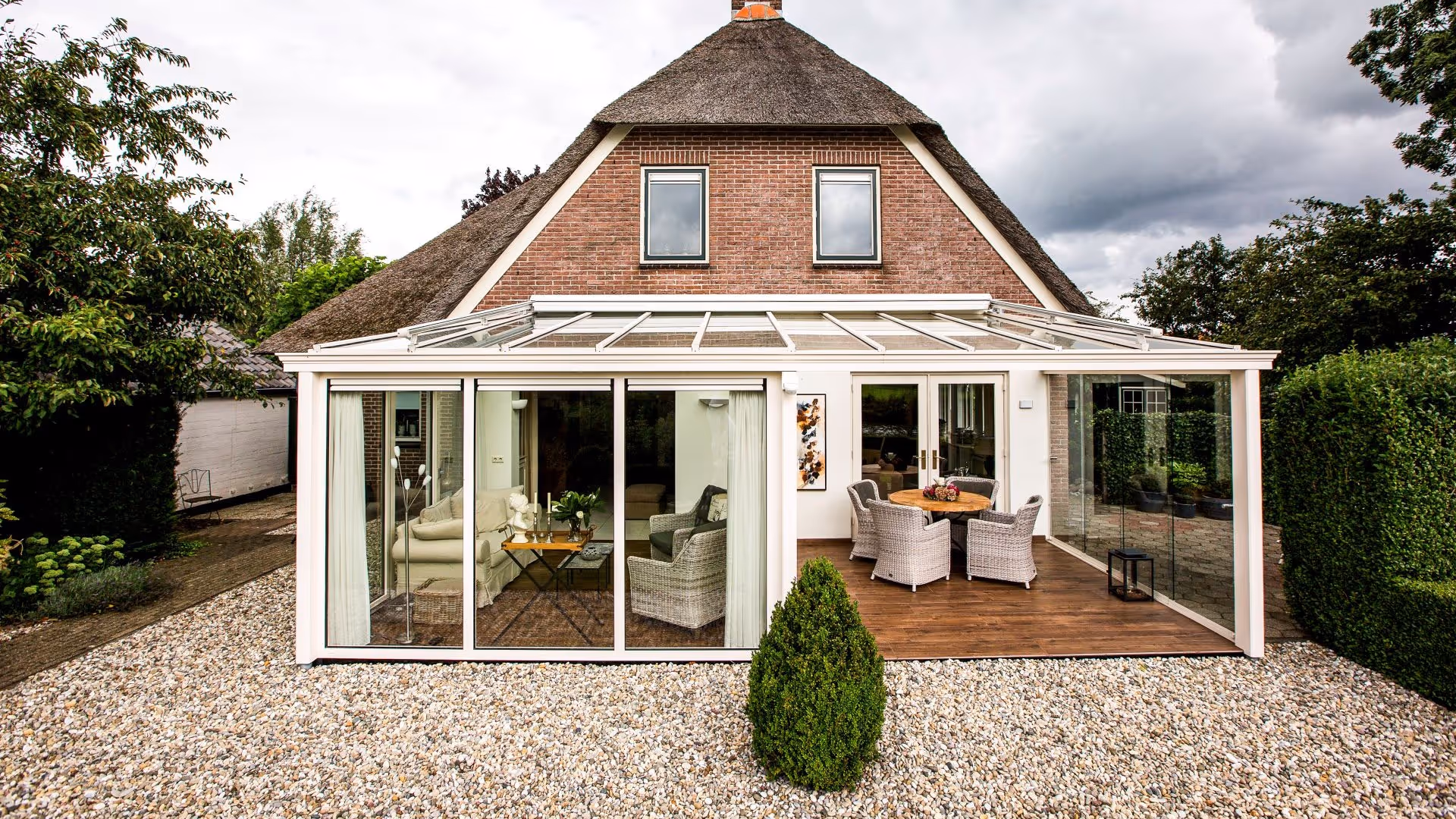 Achteraanzicht van de woning met aluminium tuinkamer en volledig glazen wanden