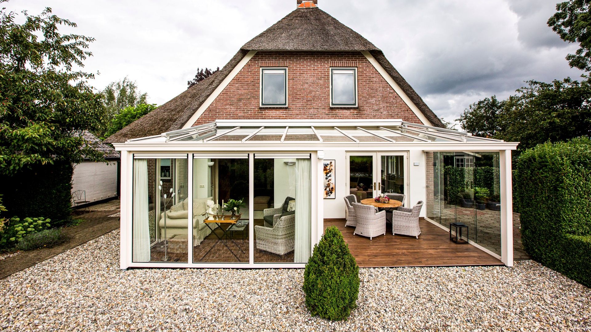 Achteraanzicht van de woning met aluminium tuinkamer en volledig glazen wanden