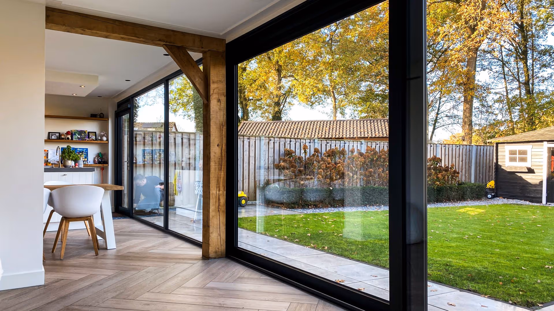 Open leefruimte met houten vloer en moderne schuifpui die direct toegang geeft tot het terras en de tuin