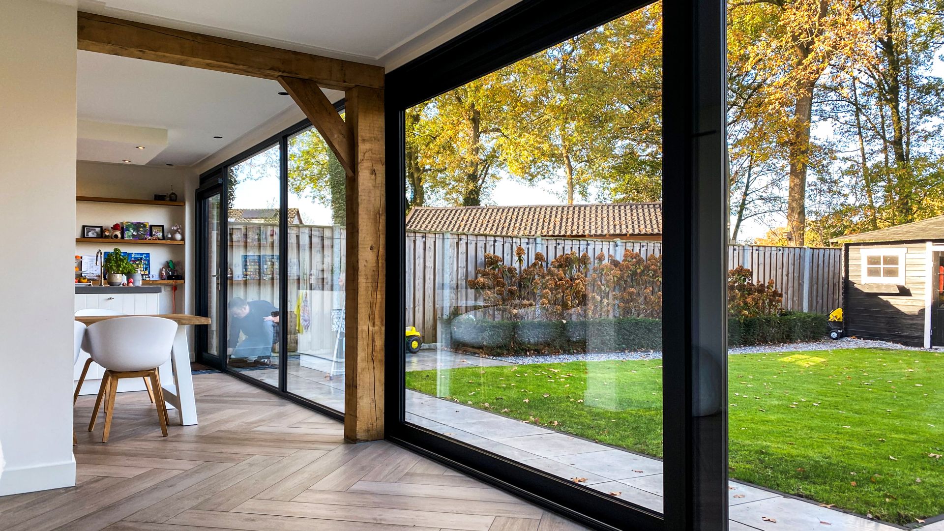 Open leefruimte met houten vloer en moderne schuifpui die direct toegang geeft tot het terras en de tuin