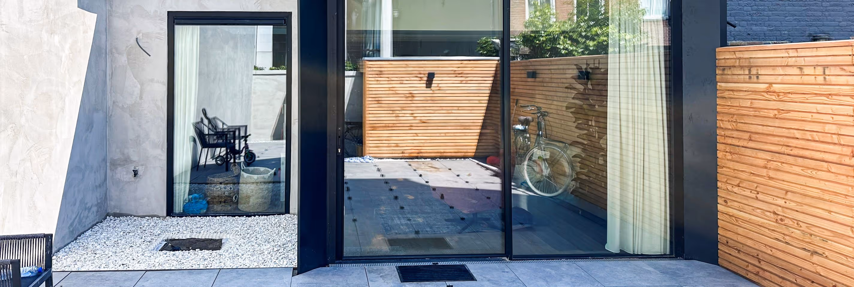 Moderne aanbouw met minimalistische zwarte schuifpui en strakke aluminium dakconstructie