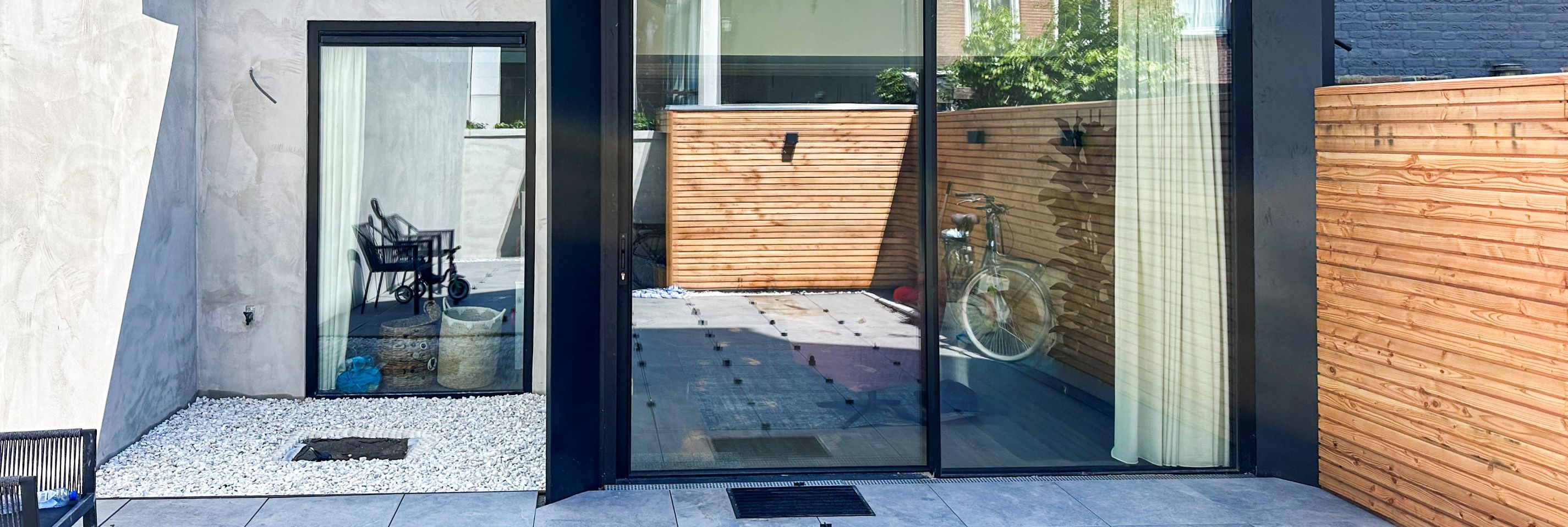 Moderne aanbouw met minimalistische zwarte schuifpui en strakke aluminium dakconstructie