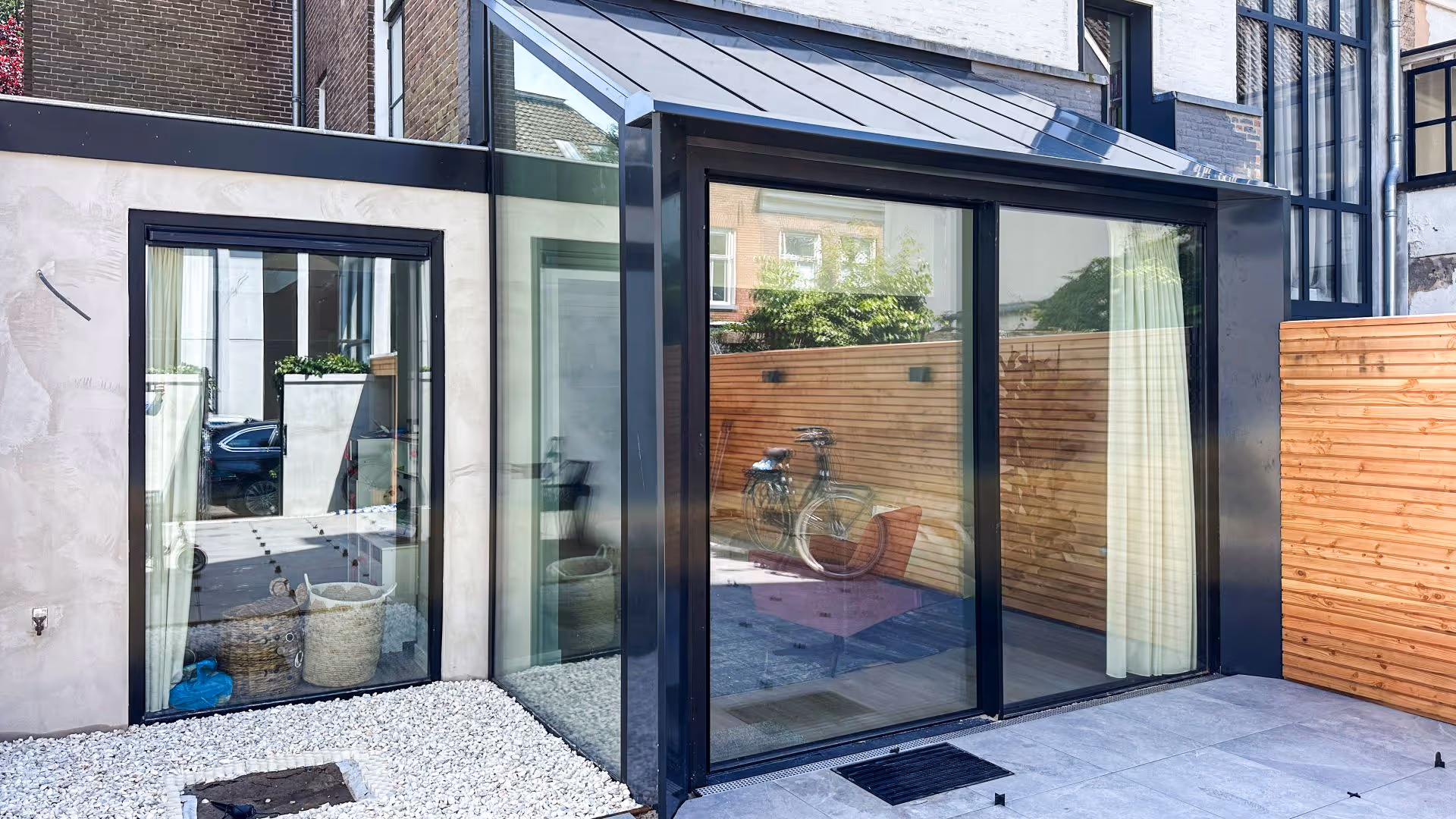 Strakke aluminium schuifpui in moderne aanbouw met glazen hoek en veel lichtinval