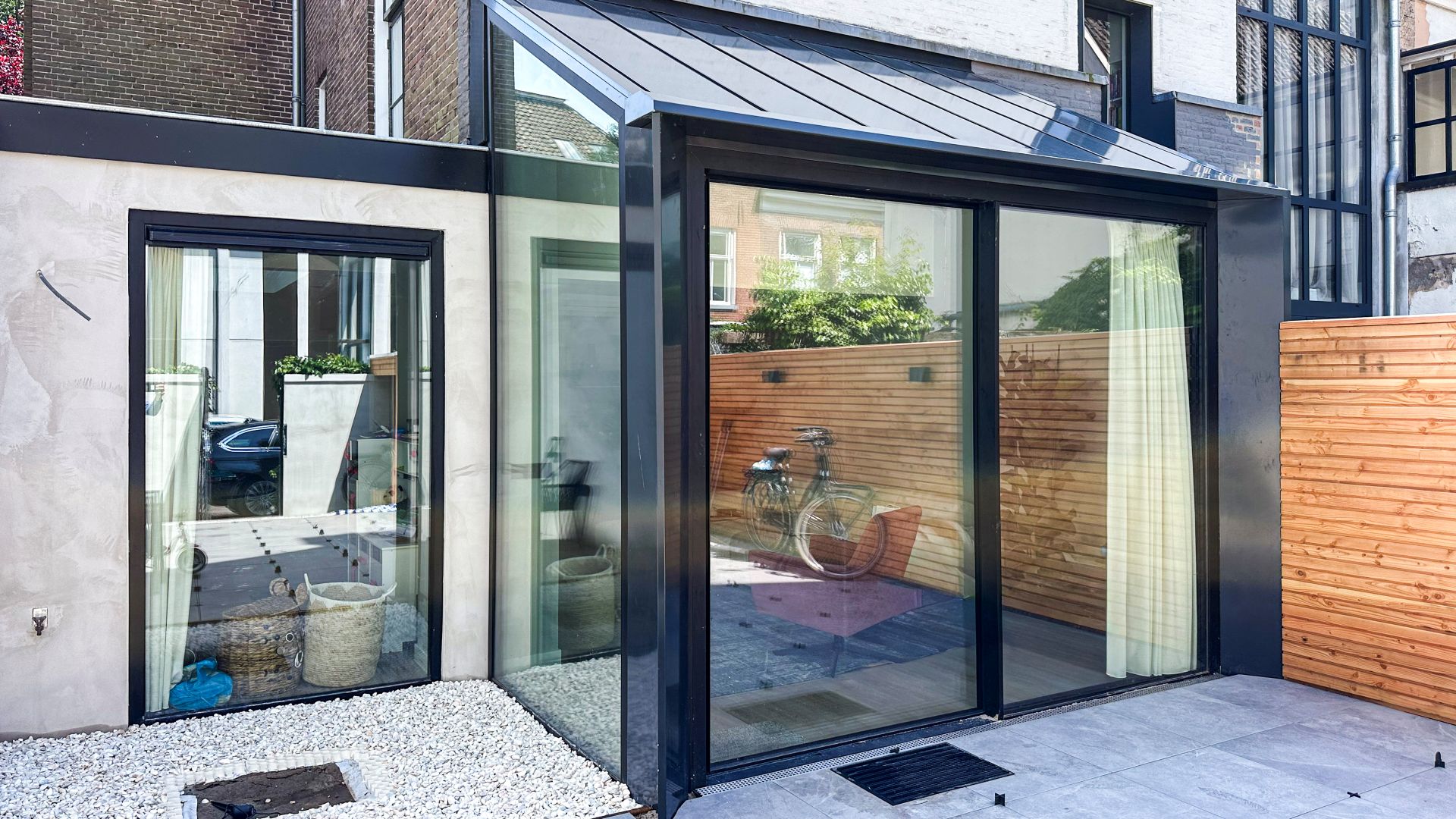 Strakke aluminium schuifpui in moderne aanbouw met glazen hoek en veel lichtinval