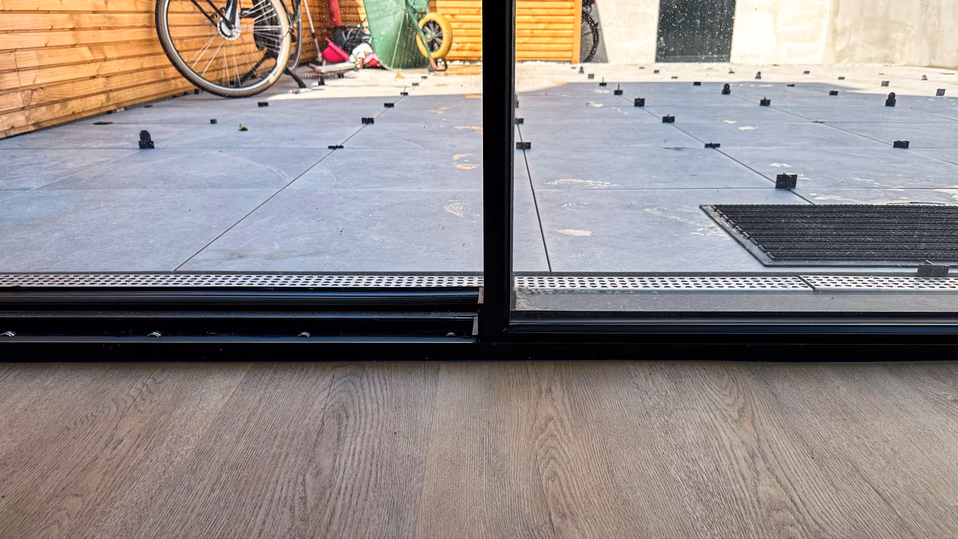 Moderne woonkamer met minimalistische schuifpui en uitzicht op een compacte stadstuin
