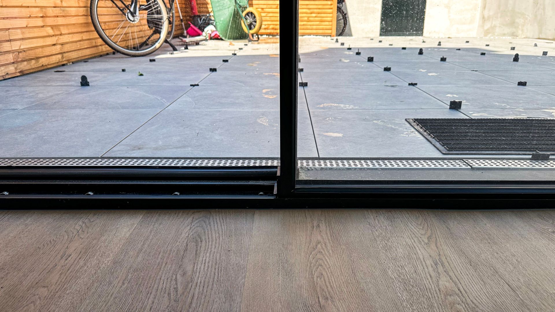 Moderne woonkamer met minimalistische schuifpui en uitzicht op een compacte stadstuin