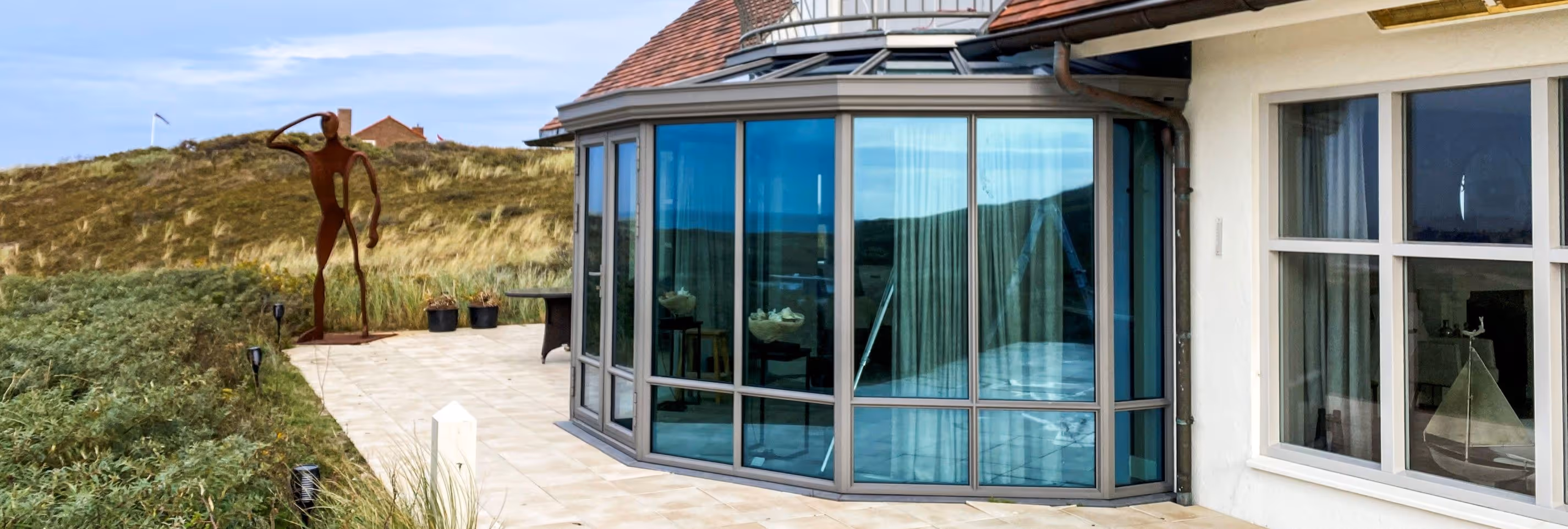 Steellook serre met slanke profielen en panoramisch uitzicht op duinlandschap