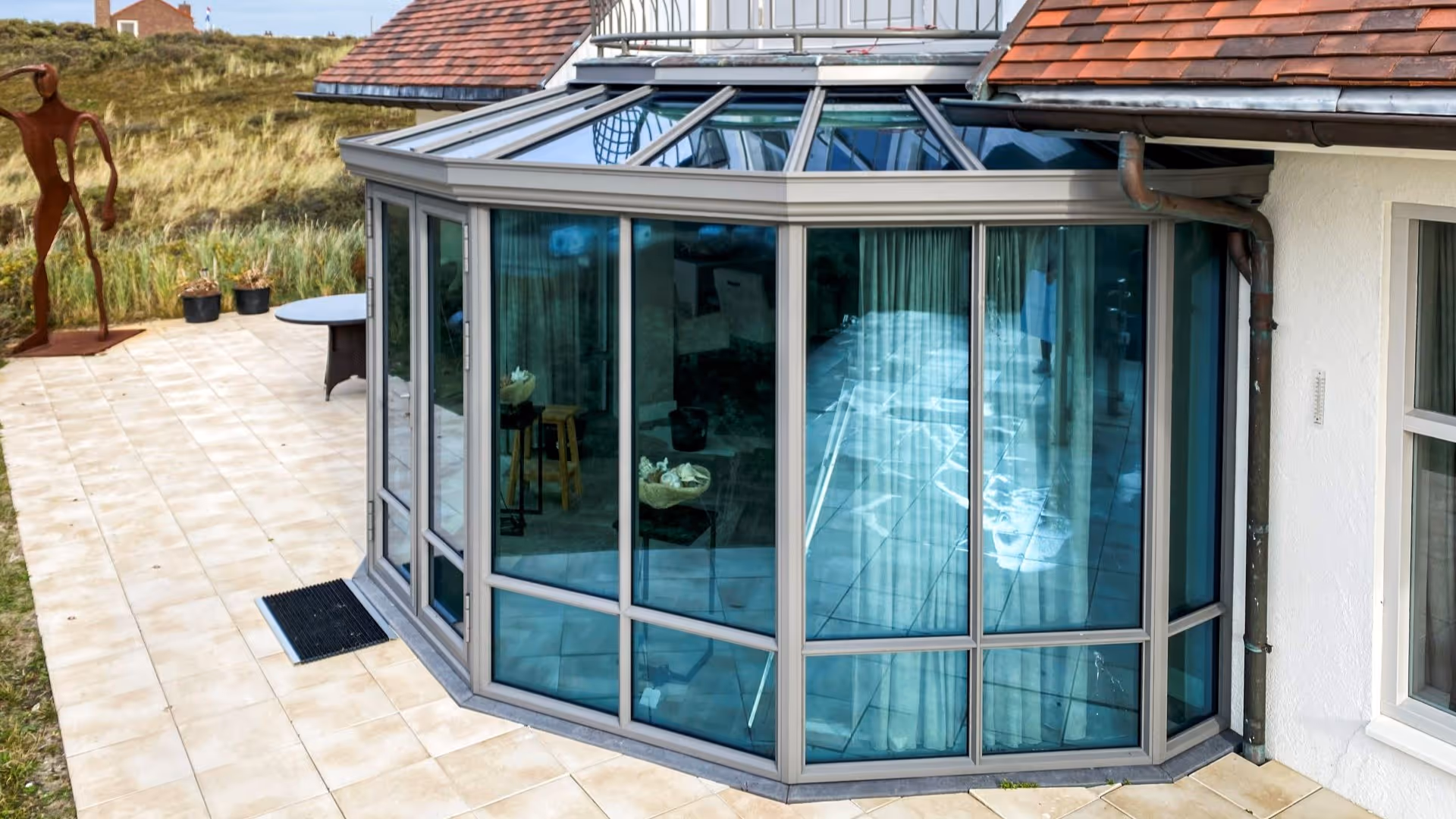 Buitenaanzicht van ronde steellook serre met glazen dak en slanke profielen