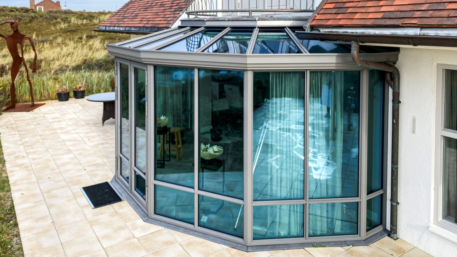 Buitenaanzicht van ronde steellook serre met glazen dak en slanke profielen