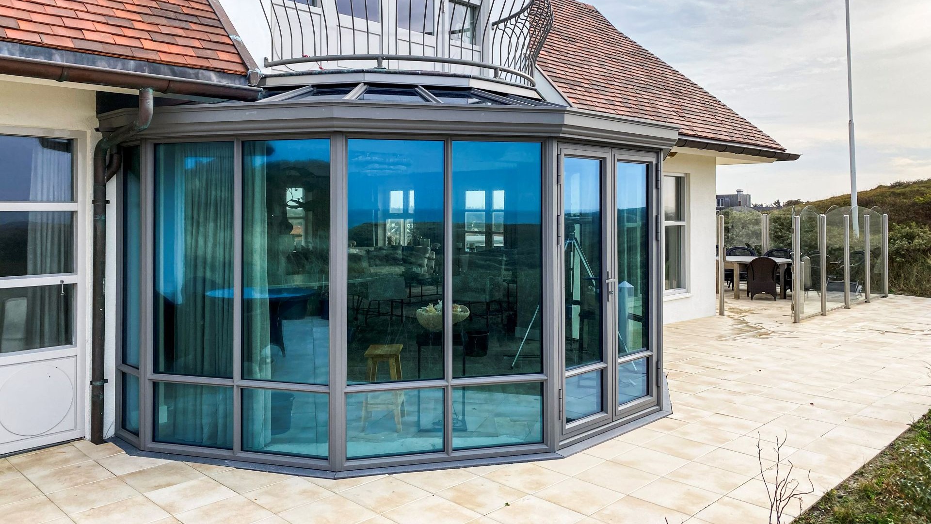 Steellook serre met gebogen glaspartijen en openslaande deur naar buitenterras