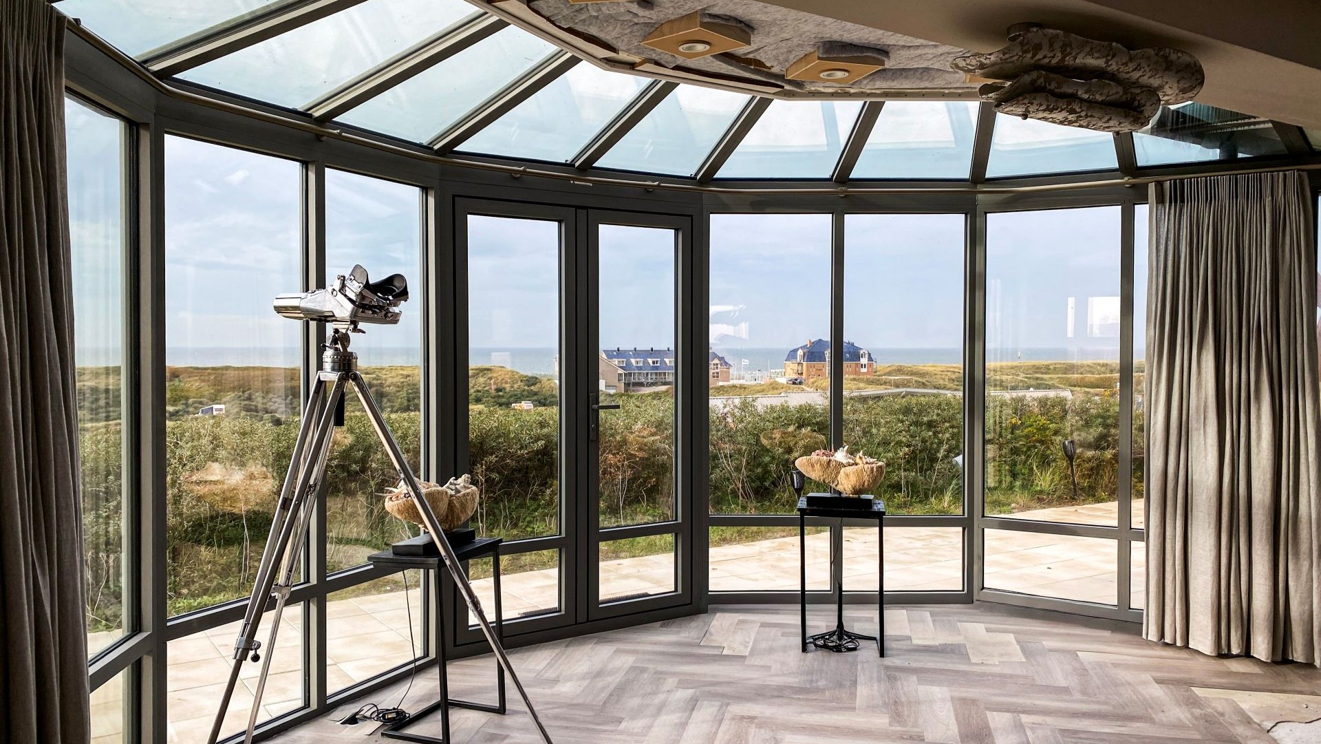 Interieur van steellook serre met glazen dak en uitzicht op zee en duinen