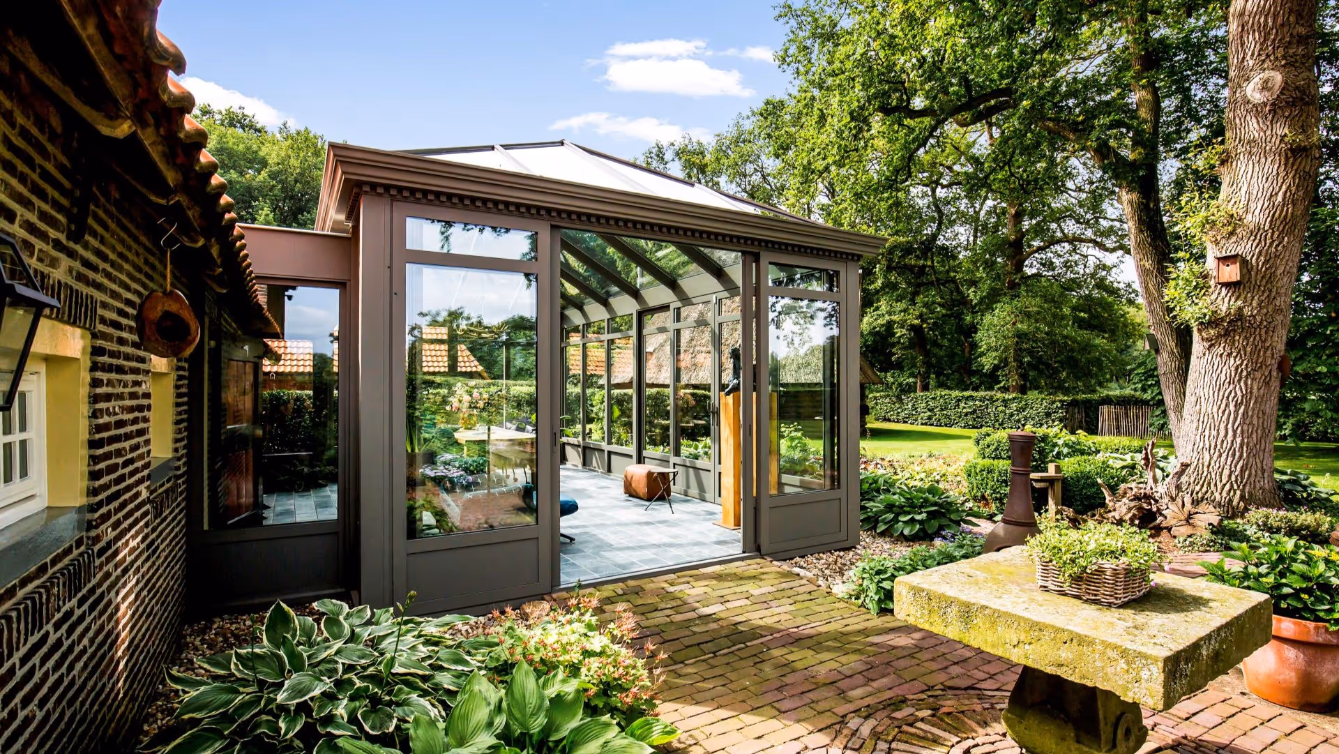 Breed tuinbeeld met serre en landelijke woning
