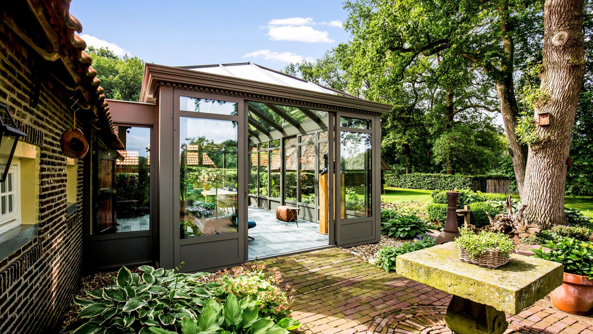  Breed tuinbeeld met serre en landelijke woning