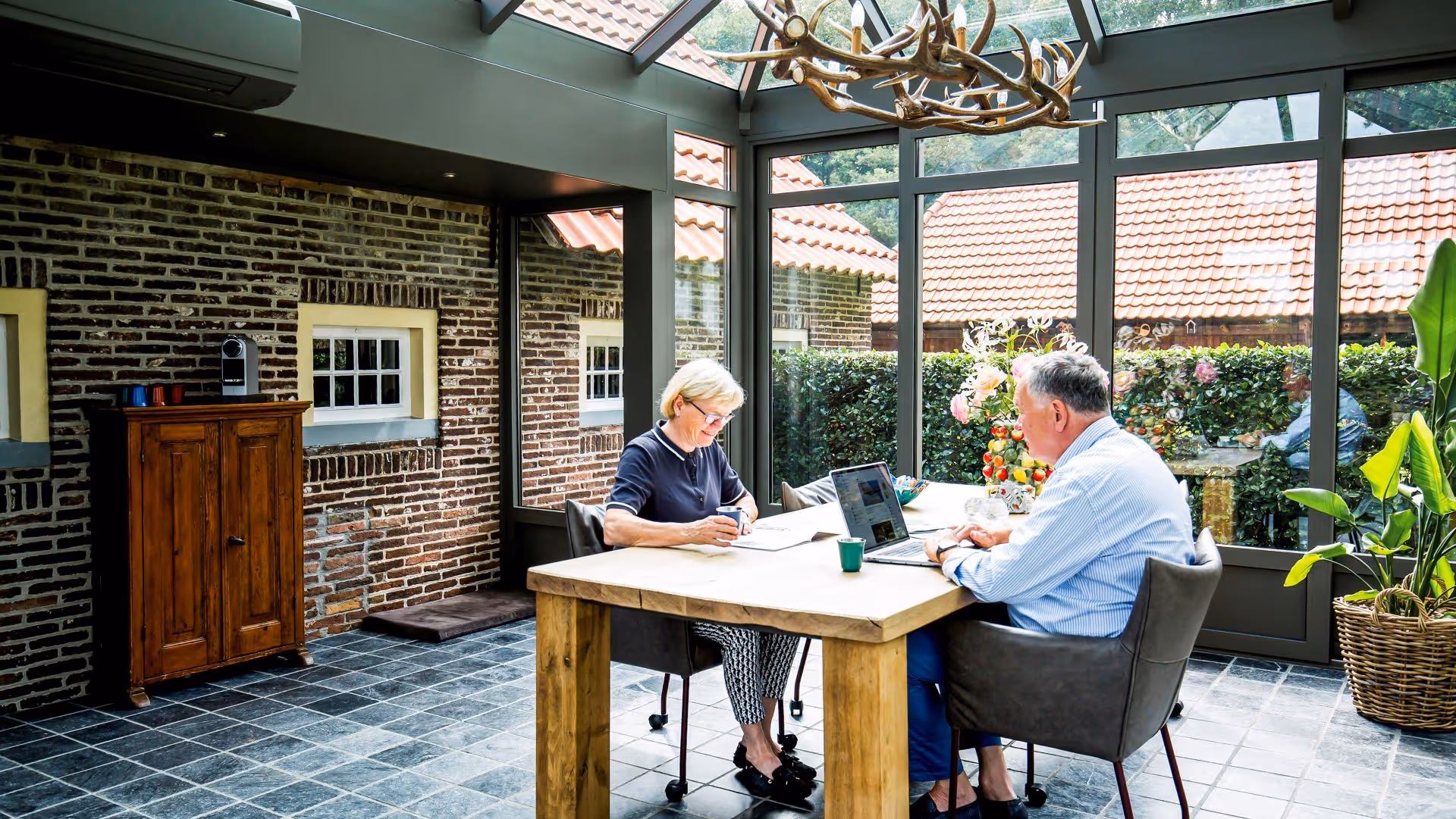 Gezellige steellook serre met houten tafel en uitzicht op groene tuin