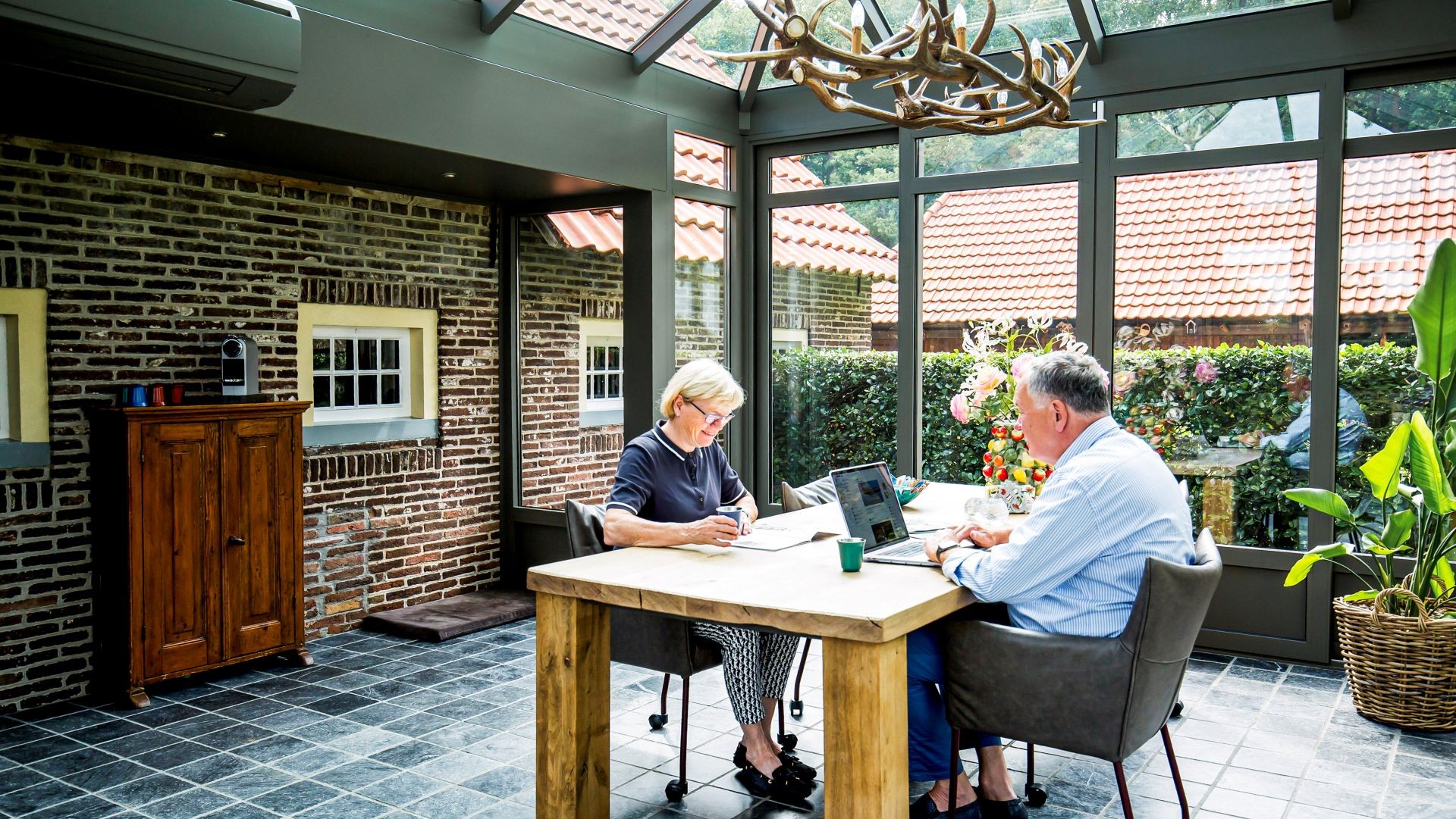 Gezellige steellook serre met houten tafel en uitzicht op groene tuin
